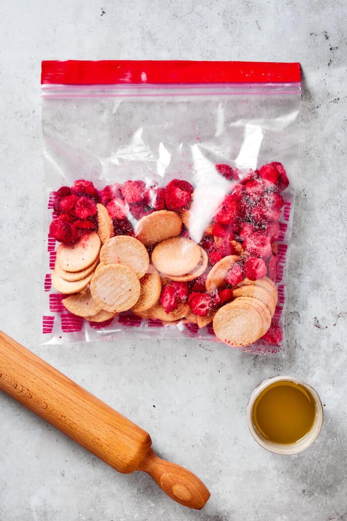 Creamy and sweet with a bit of crunch, Strawberry Crunch Cake is bursting with fruit flavor! This bright strawberry dessert is a favorite. Oreos and freeze-dried strawberries are in a plastic bag ready to be pulverized with a baking pin.