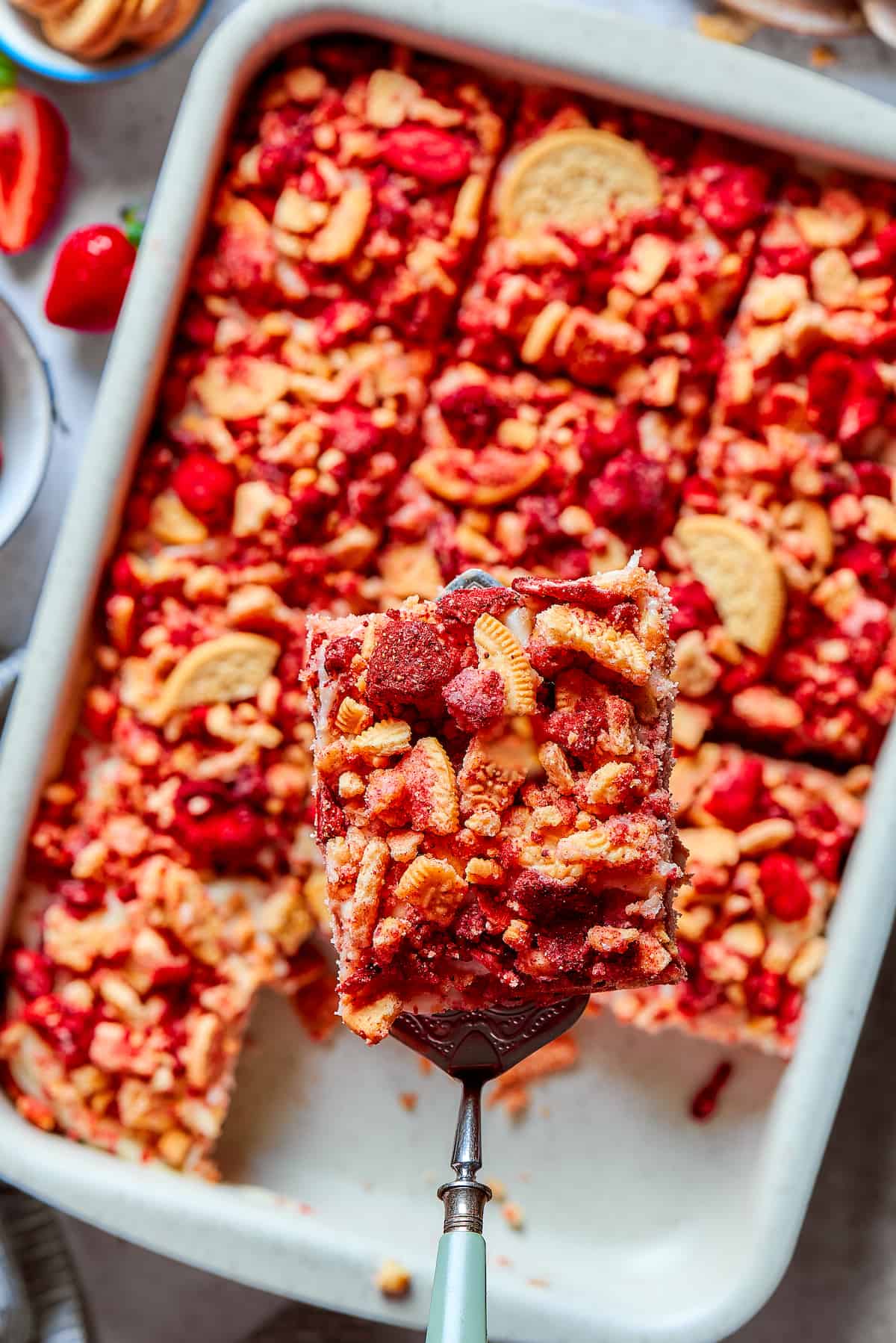Creamy and sweet with a bit of crunch, Strawberry Crunch Cake is bursting with fruit flavor! This bright strawberry dessert is a favorite. A piece of strawberry crunch cake is lifted out of a pan.