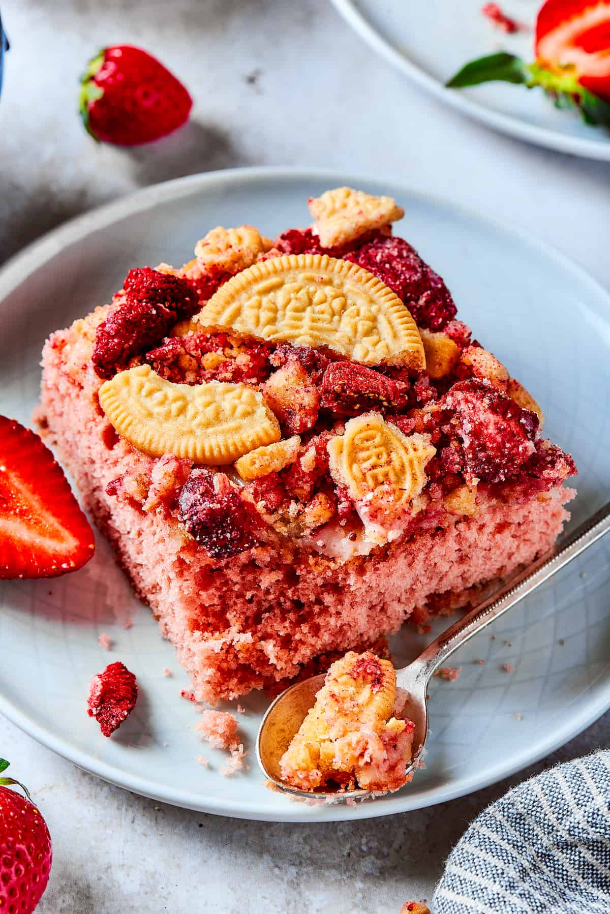 Creamy and sweet with a bit of crunch, Strawberry Crunch Cake is bursting with fruit flavor! This bright strawberry dessert is a favorite. Pieces of strawberry crunch cake on plates with strawberries.