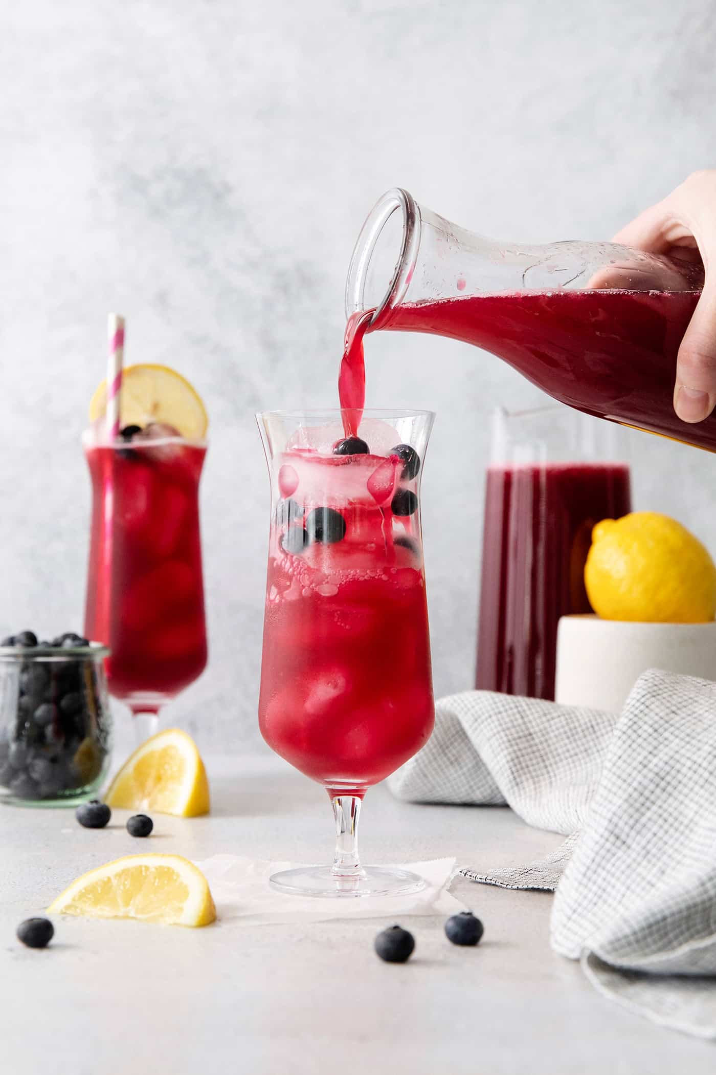 This Blueberry Lemonade is the perfect summertime drink! It’s fruity and refreshing with tart lemons and sweet blueberries. Blueberry lemonade being poured into a glass over ice