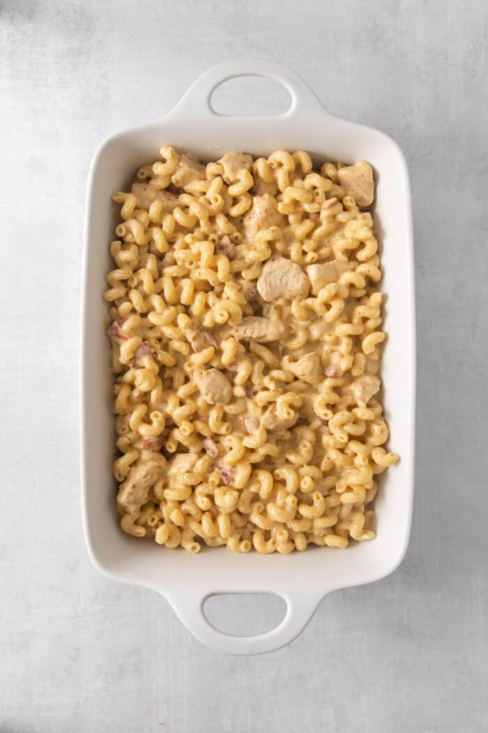 This Chicken Bacon Ranch Pasta is a perfect family-friendly meal loaded with flavor! Bacon, chicken, and pasta are baked in a creamy sauce. The ingredients for chicken ranch pasta are placed in a large baking dish.