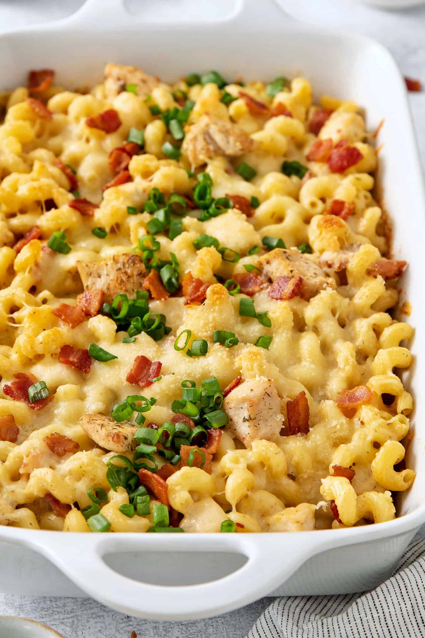 This Chicken Bacon Ranch Pasta is a perfect family-friendly meal loaded with flavor! Bacon, chicken, and pasta are baked in a creamy sauce. A close up shot shows chicken ranch pasta covered with sliced green onions.