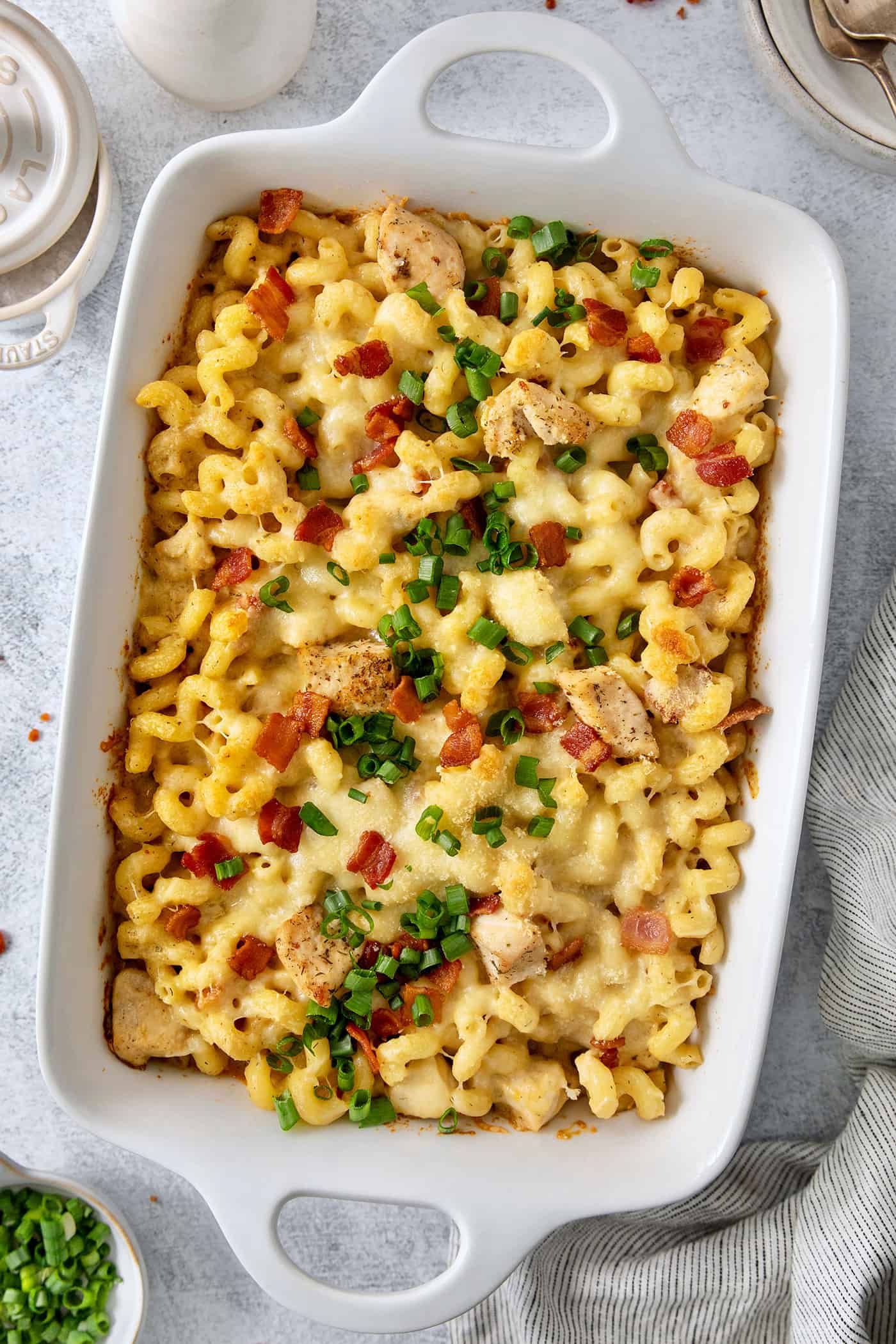 This Chicken Bacon Ranch Pasta is a perfect family-friendly meal loaded with flavor! Bacon, chicken, and pasta are baked in a creamy sauce. A baking dish is full of chicken ranch pasta covered with sliced green onions, chicken, and bacon.