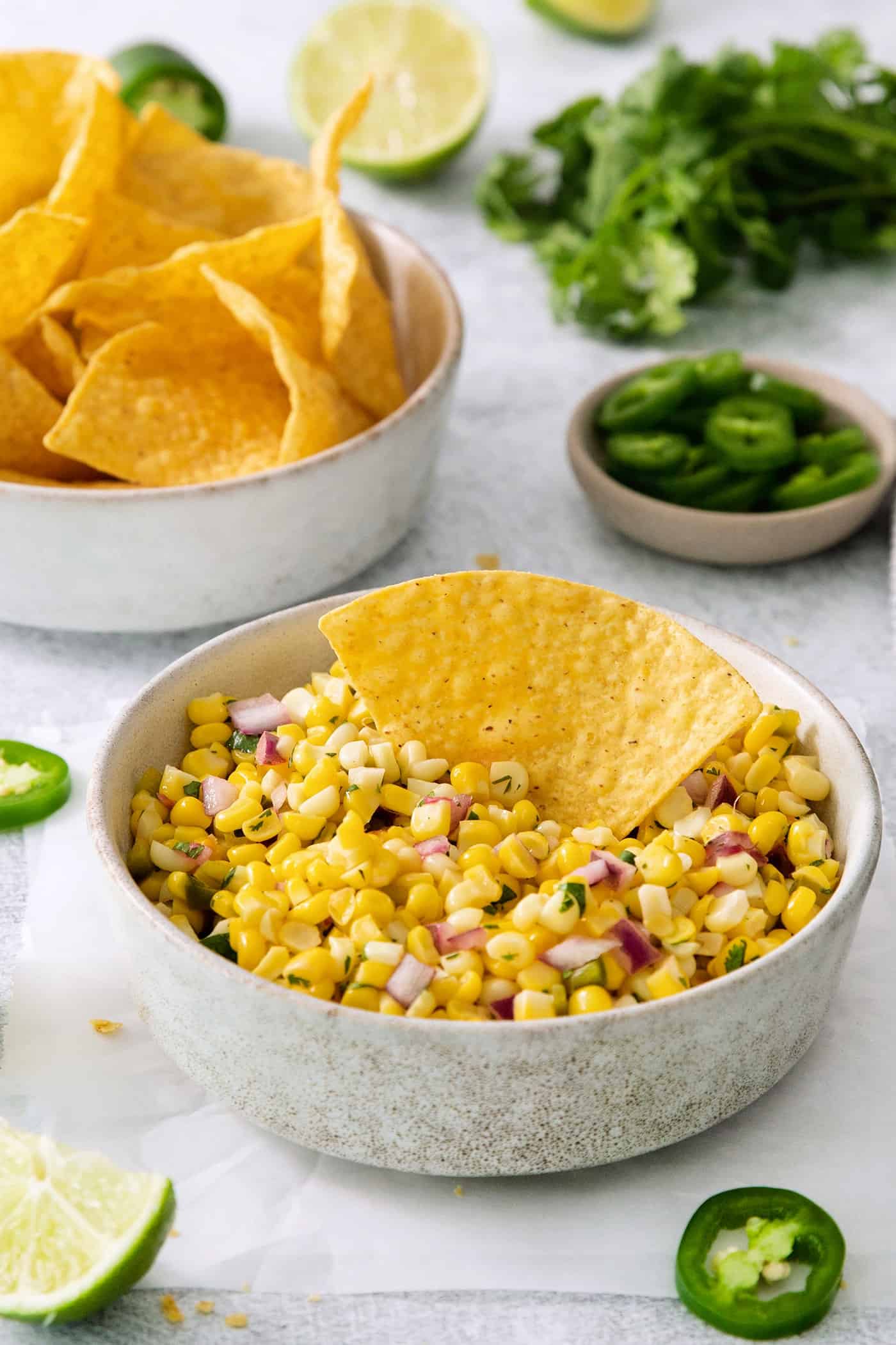 A tortilla chip in a bowl of Chipotle corn salsa