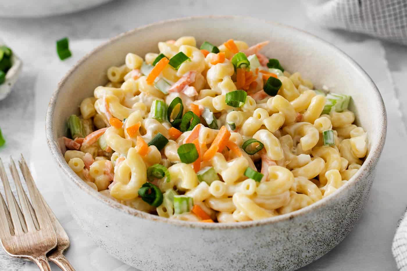 Hawaiian Macaroni Salad is always a hit at summer barbecues! It's a quick and easy side dish that goes perfectly with grilled meats. A close up shot of hawaiian macaroni salad topped with chopped vegetables.