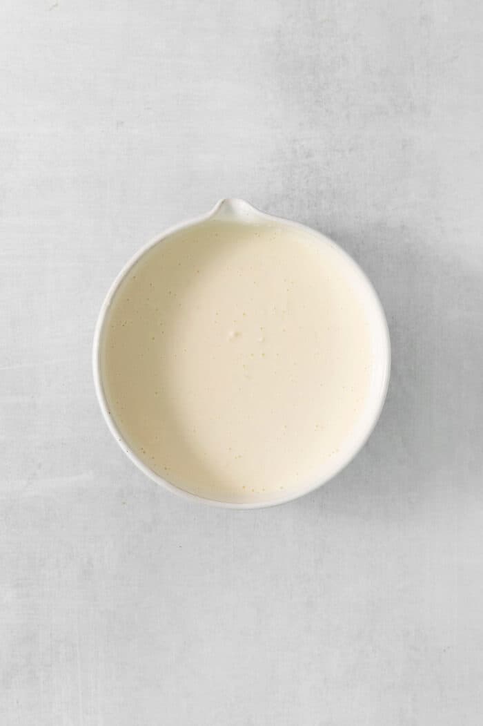 Hawaiian Macaroni Salad is always a hit at summer barbecues! It's a quick and easy side dish that goes perfectly with grilled meats. Mayonnaise dressing in a white bowl on a white background.
