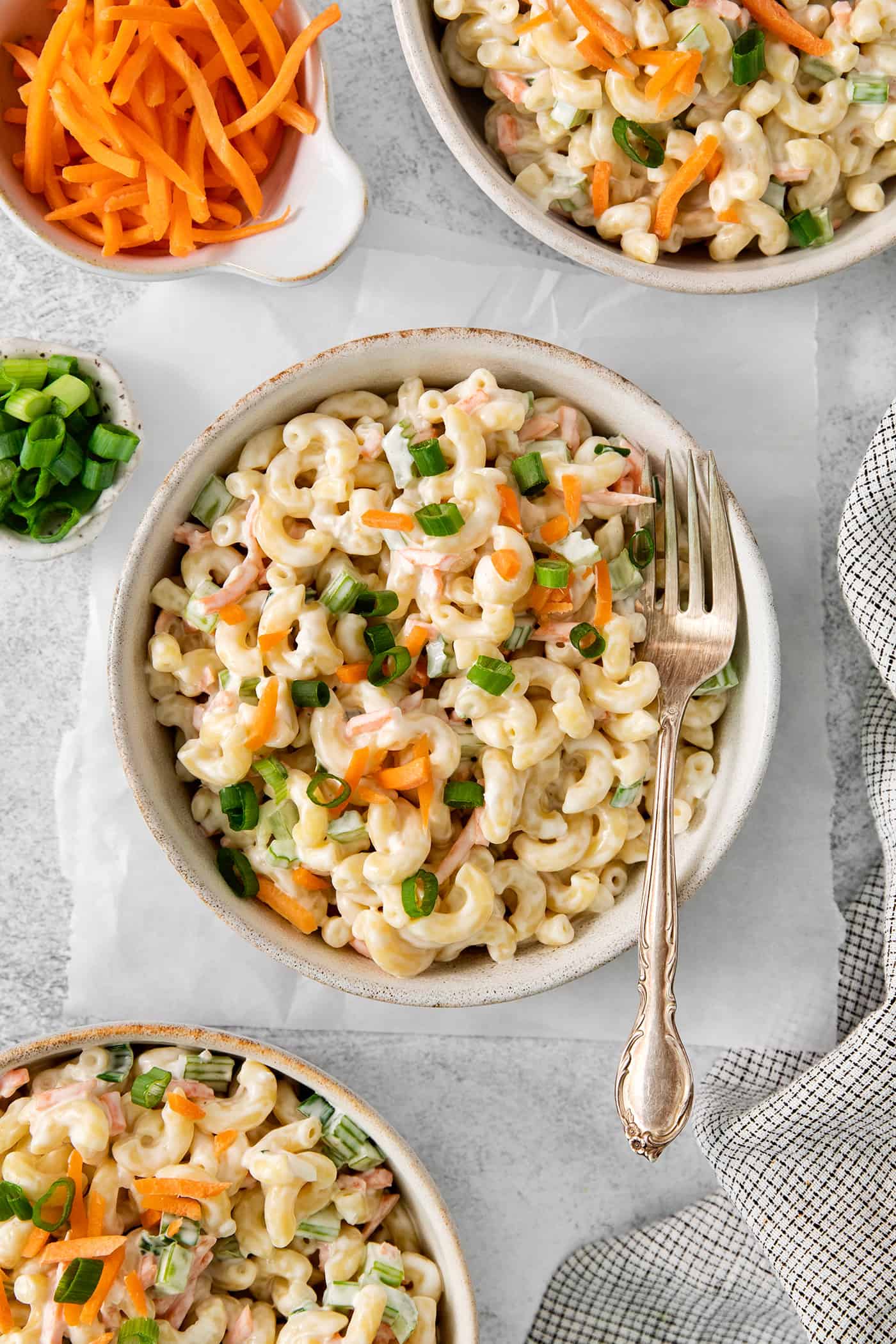 Hawaiian Macaroni Salad is always a hit at summer barbecues! It's a quick and easy side dish that goes perfectly with grilled meats. Bowls of hawaiian macaroni salad are seen in white bowls on a table with forks.