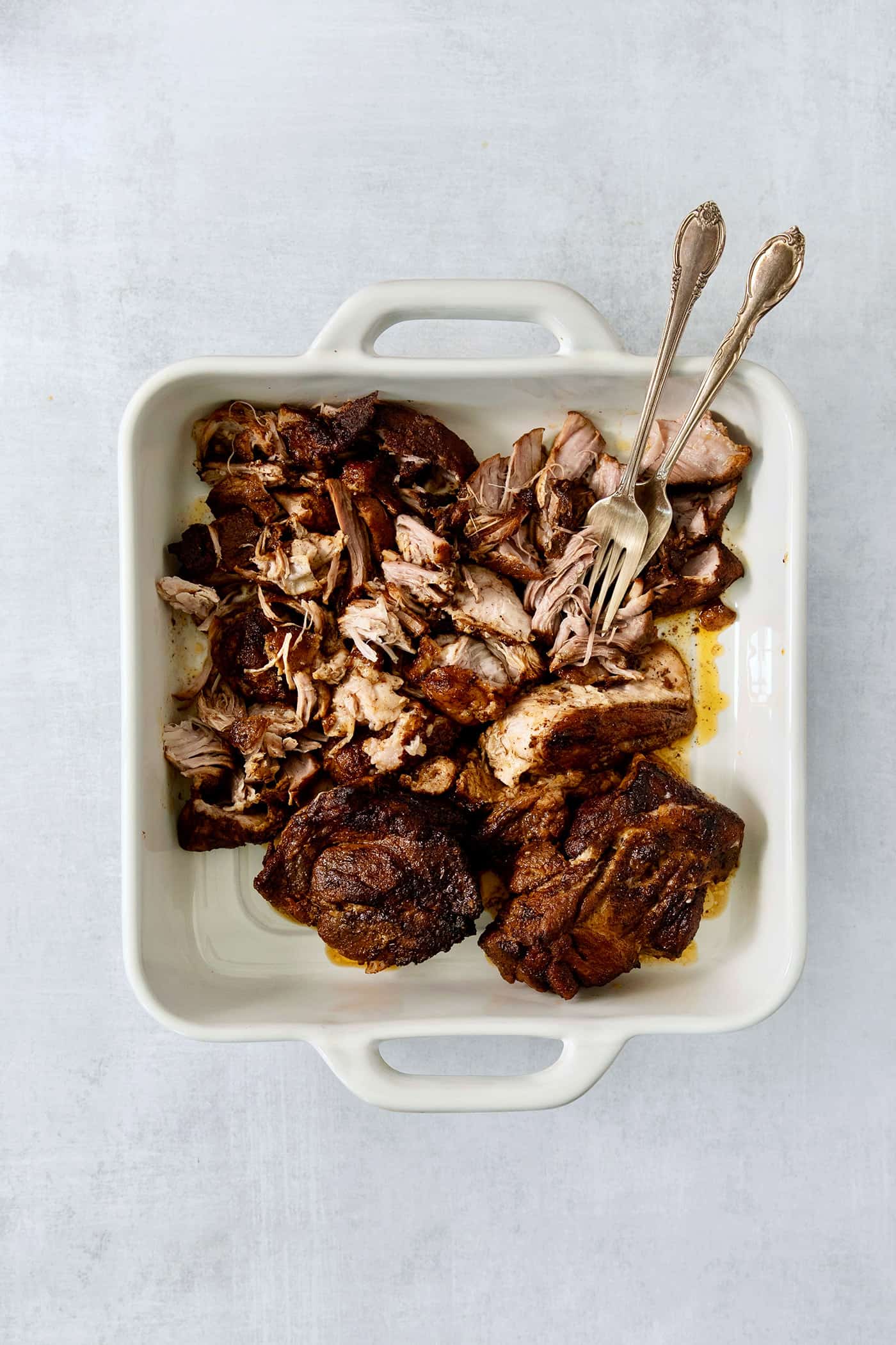 Incredibly tender and a little bit spicy, this easy Pulled Pork recipe is an absolute keeper. It's also super flavorful and versatile. Shredding cooked pork with two forks.