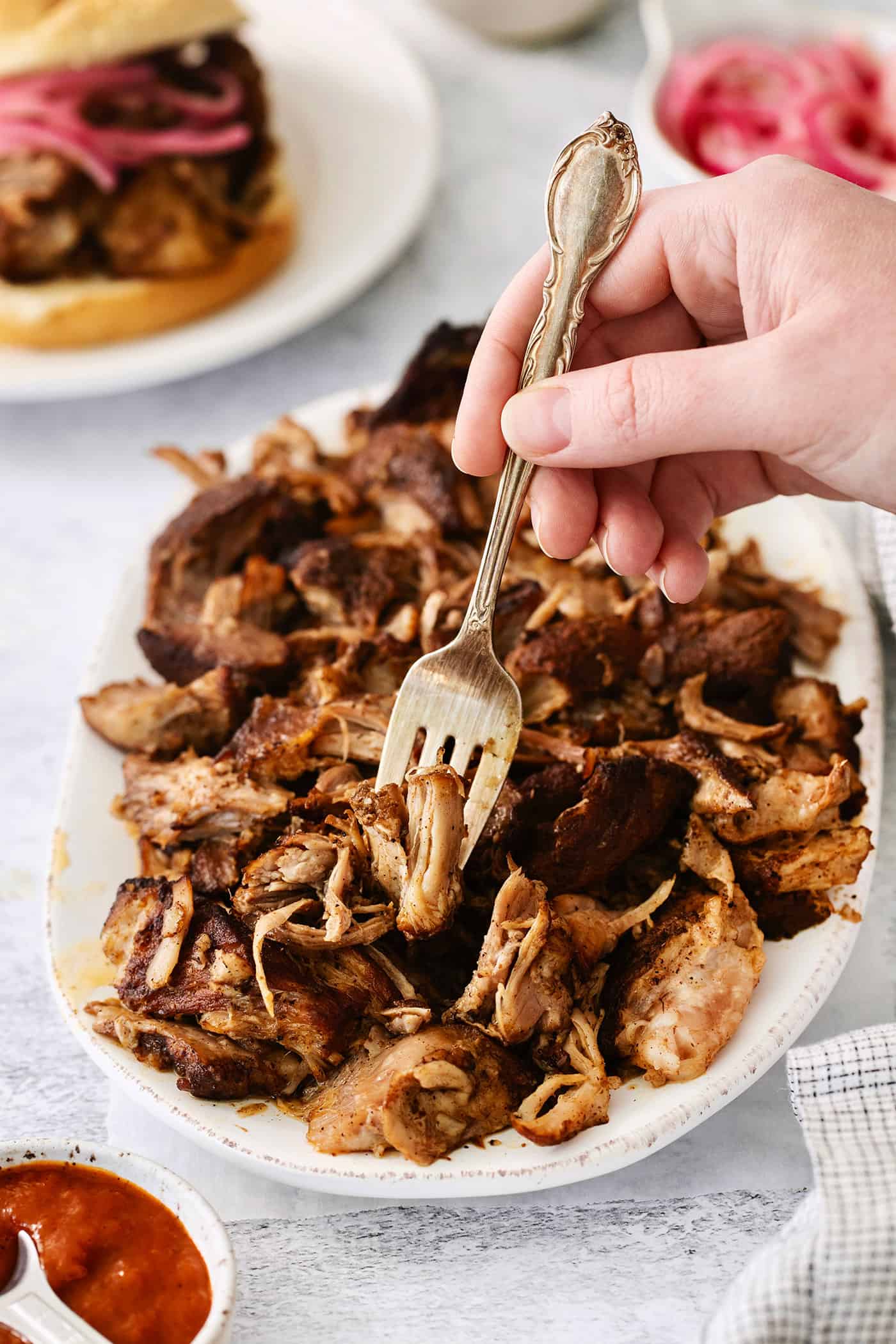A fork digs into a plate of pulled pork.