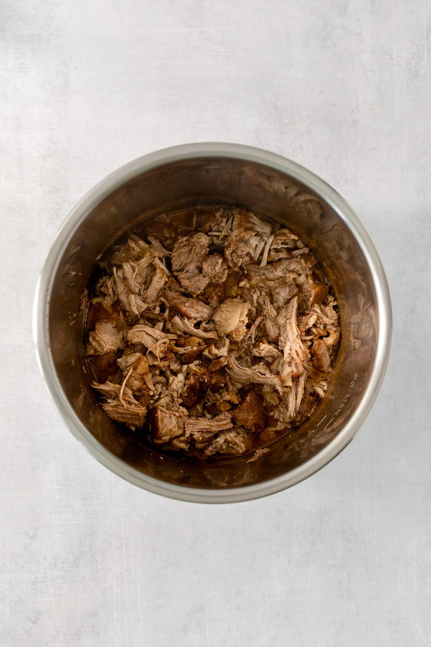 Incredibly tender and a little bit spicy, this easy Pulled Pork recipe is an absolute keeper. It's also super flavorful and versatile. Pork is shown in an Instant Pot.