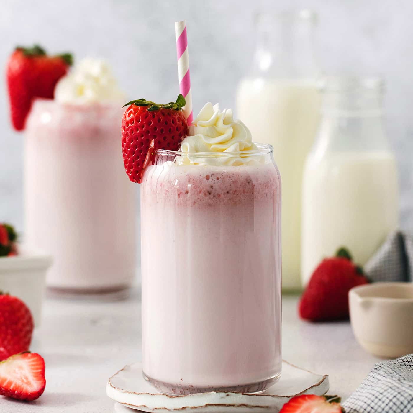 Creamy, refreshing, and full of fresh strawberry flavor, this Strawberry Milk recipe is quick and easy to make with only 4 ingredients! Glasses of strawberry milk with milk in the background.
