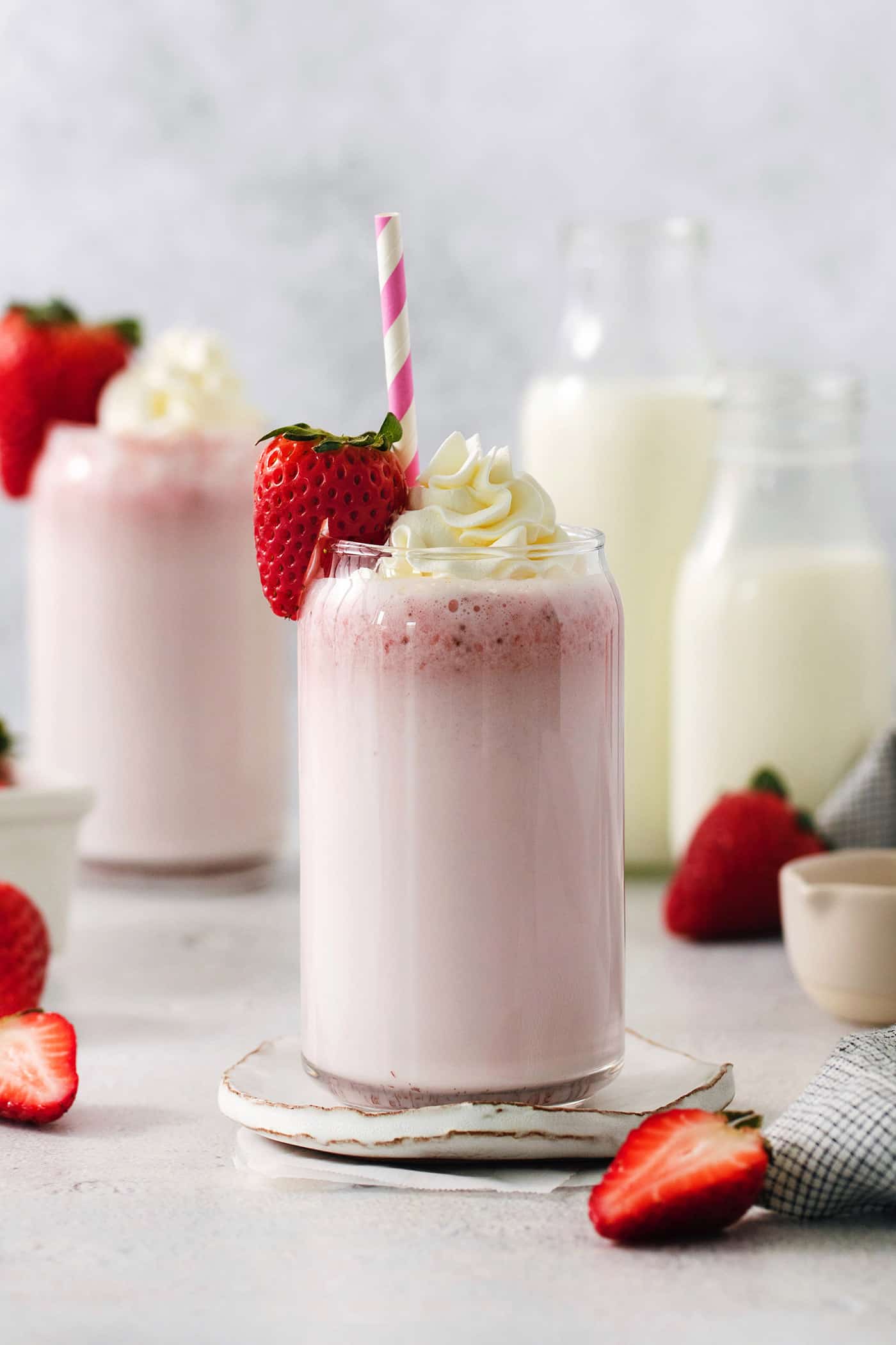 Refreshing and beautiful, Strawberry Milk is beyond simple to make! You'll need just 4 ingredients and a few minutes to whip up glasses of this strawberry-laden drink. Glasses of strawberry milk with milk in the background.