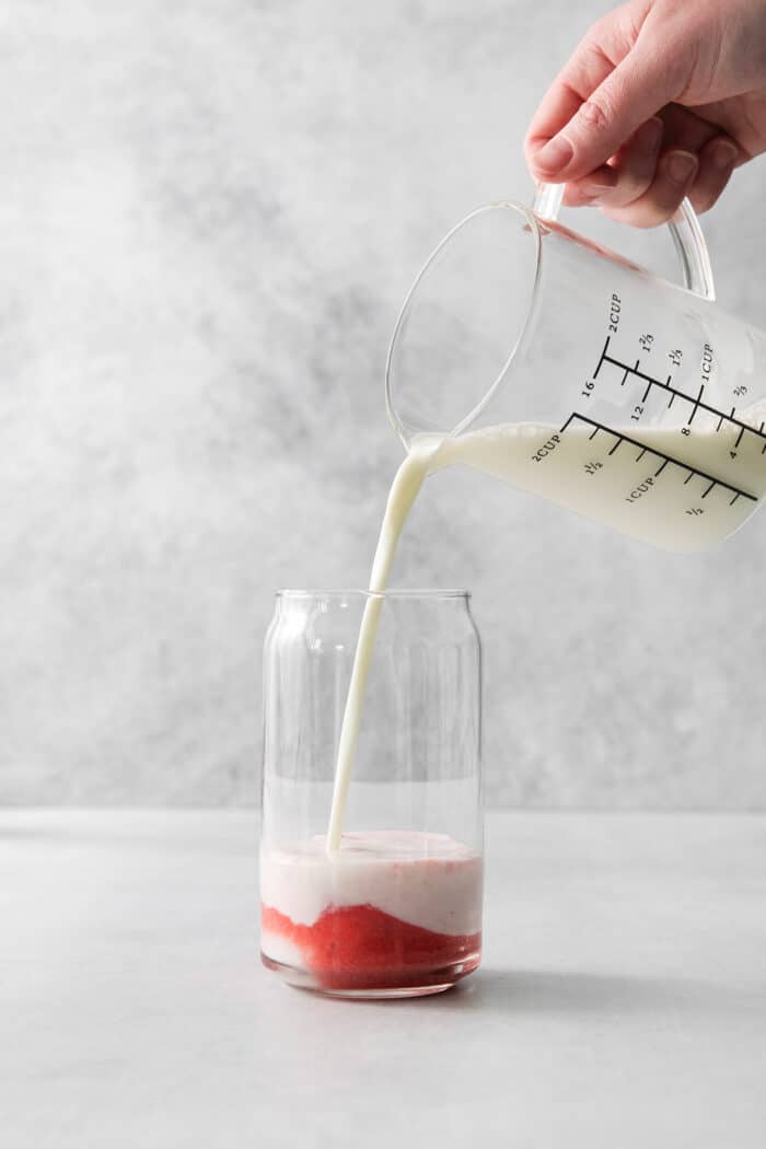 Refreshing and beautiful, Strawberry Milk is beyond simple to make! You'll need just 4 ingredients and a few minutes to whip up glasses of this strawberry-laden drink. Pouring milk into strawberry puree.