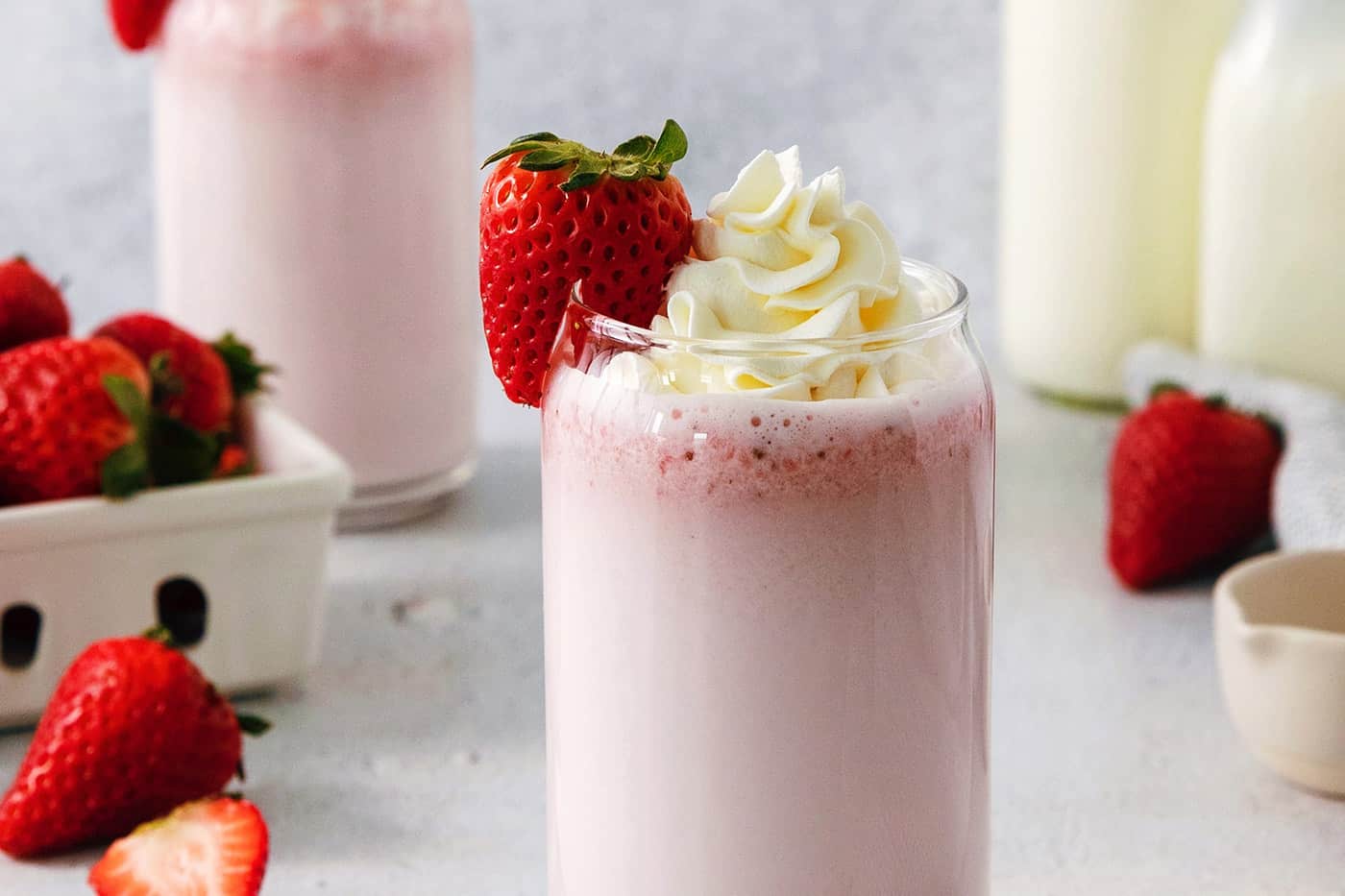 Refreshing and beautiful, Strawberry Milk is beyond simple to make! You'll need just 4 ingredients and a few minutes to whip up glasses of this strawberry-laden drink. Glasses of strawberry milk with milk in the background.