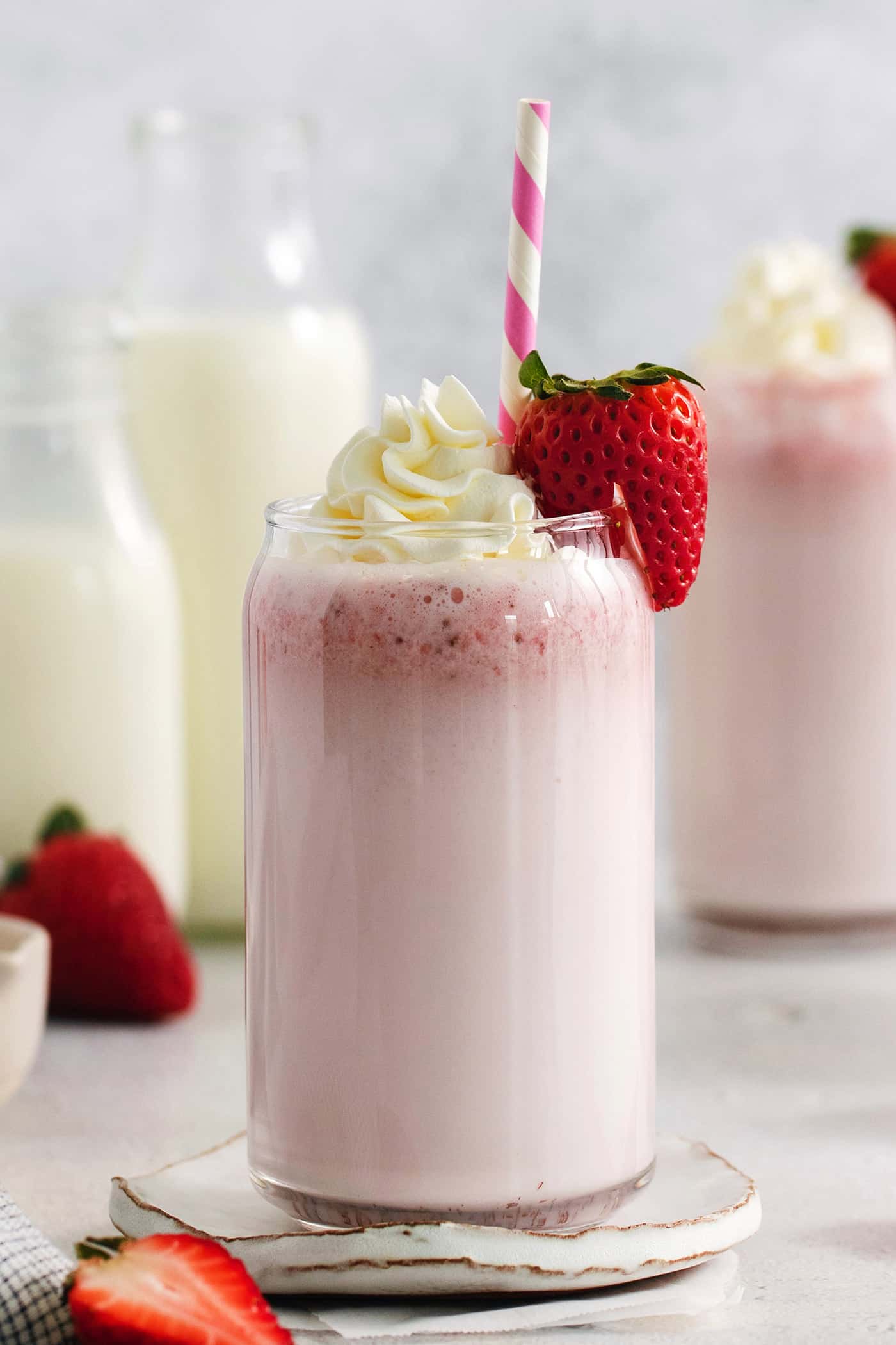 Refreshing and beautiful, Strawberry Milk is beyond simple to make! You'll need just 4 ingredients and a few minutes to whip up glasses of this strawberry-laden drink. Glasses of strawberry milk with milk in the background.