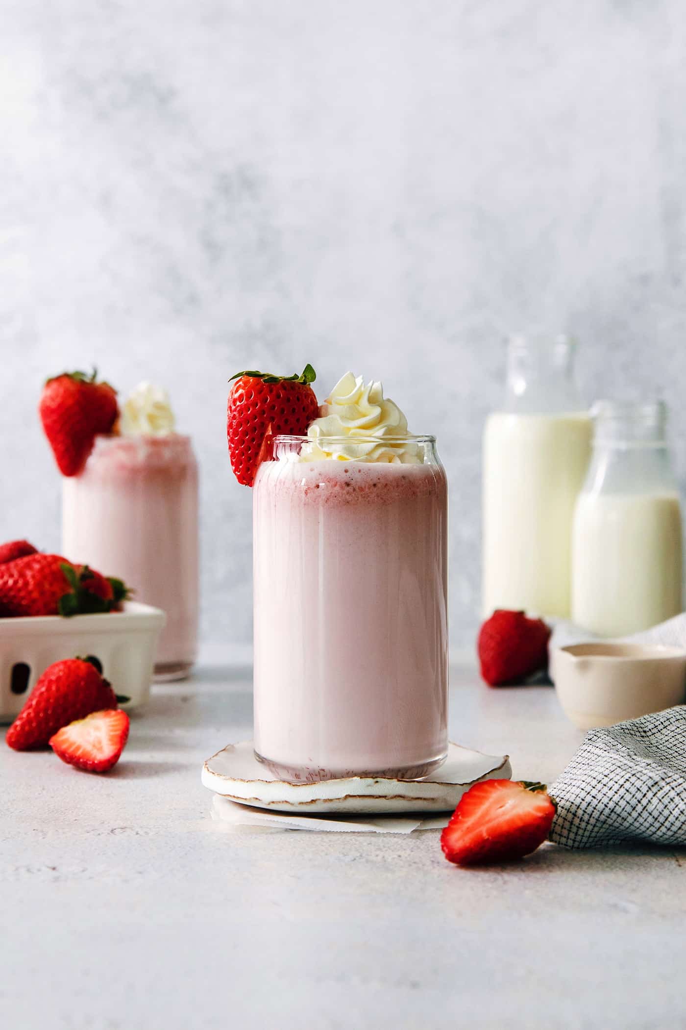 Refreshing and beautiful, Strawberry Milk is beyond simple to make! You'll need just 4 ingredients and a few minutes to whip up glasses of this strawberry-laden drink. Glasses of strawberry milk with milk in the background.