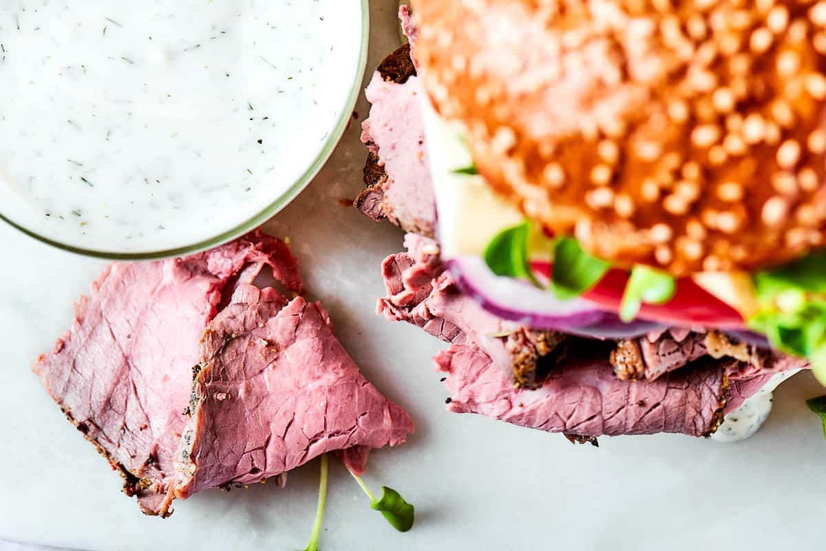 Loaded with lots of melted Swiss cheese, this Roast Beef Sandwich piles thinly sliced meat, fresh greens, and mayonnaise on a toasted bun. A roast beef sandwich with toppings.