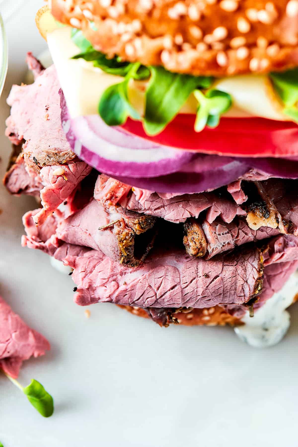 Loaded with lots of melted Swiss cheese, this Roast Beef Sandwich piles thinly sliced meat, fresh greens, and mayonnaise on a toasted bun. a close up of a roast beef sandwich.