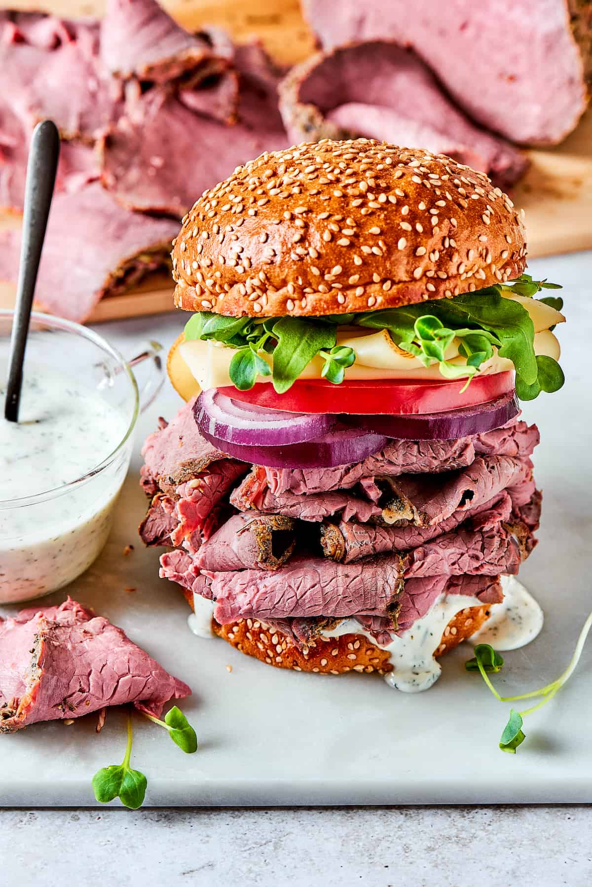 Loaded with lots of melted Swiss cheese, this Roast Beef Sandwich piles thinly sliced meat, fresh greens, and mayonnaise on a toasted bun. A roast beef sandwich with toppings.