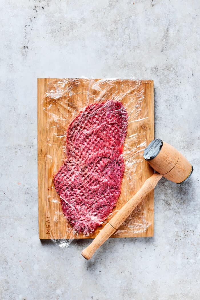 Rich, flavorful Rouladen is a classic German dish. Little meat rolls are stuffed with onions, bacon, and pickles then simmered in gravy. Prepping a beef strip.