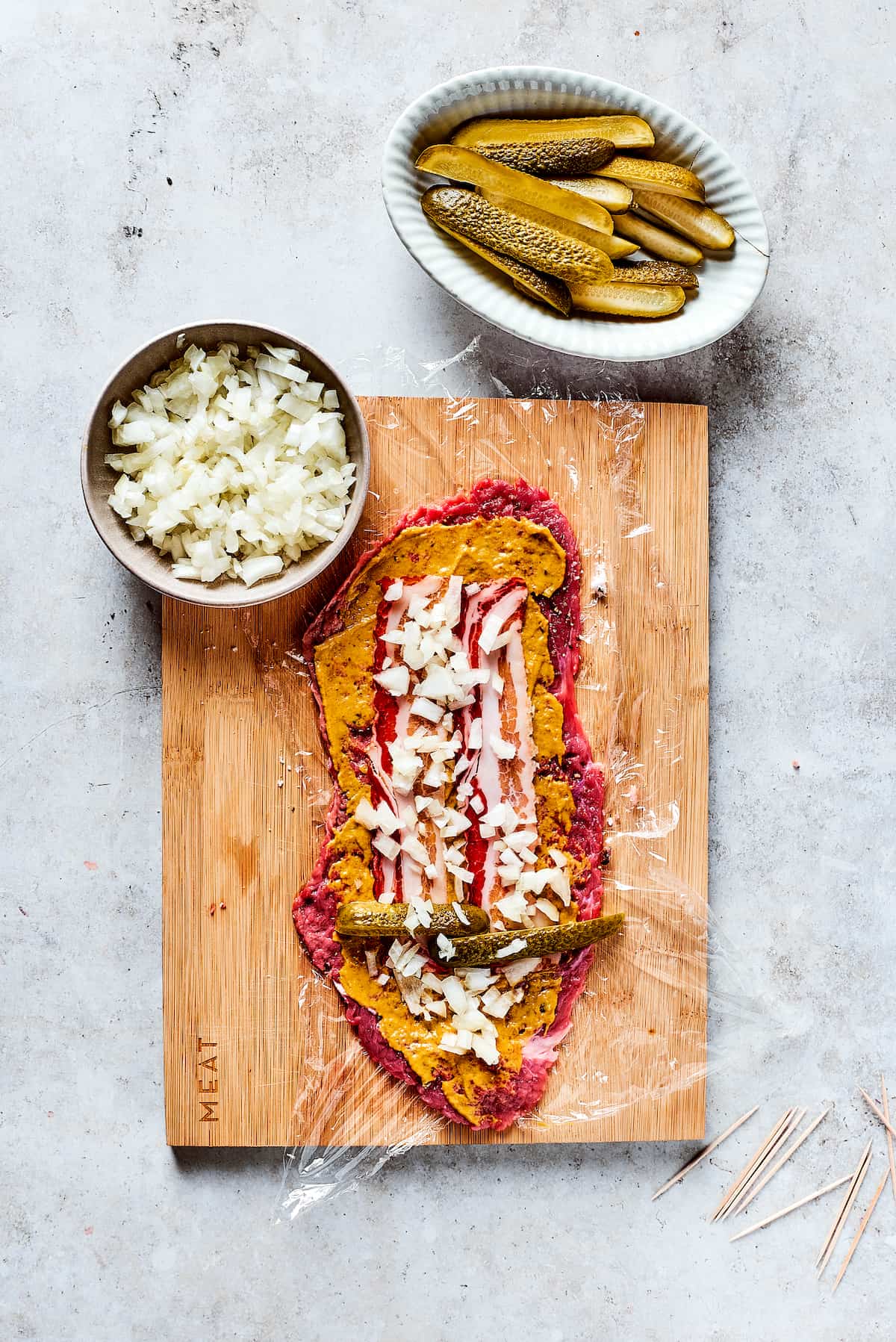 Rich, flavorful Rouladen is a classic German dish. Little meat rolls are stuffed with onions, bacon, and pickles then simmered in gravy. Adding filling to a beef strip.