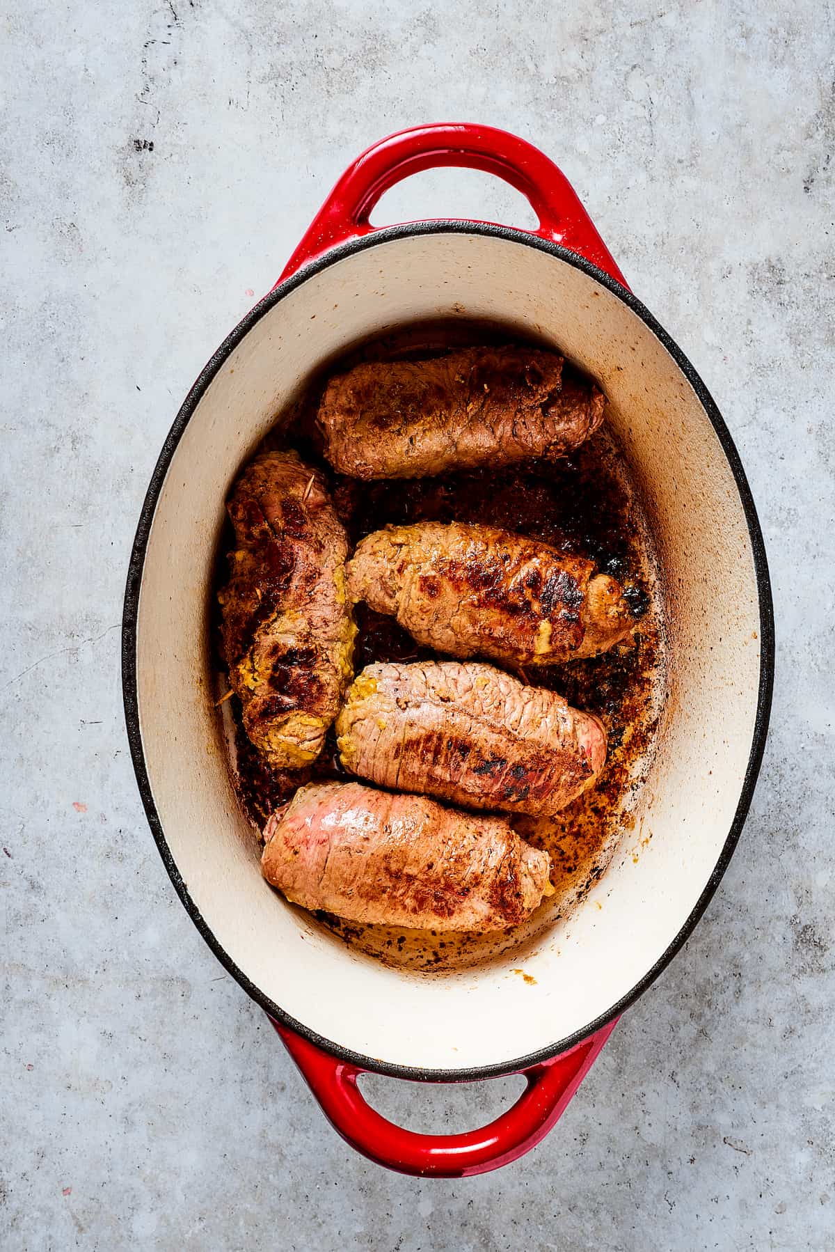 Rich, flavorful Rouladen is a classic German dish. Little meat rolls are stuffed with onions, bacon, and pickles then simmered in gravy. Beef rolls in a dutch oven.