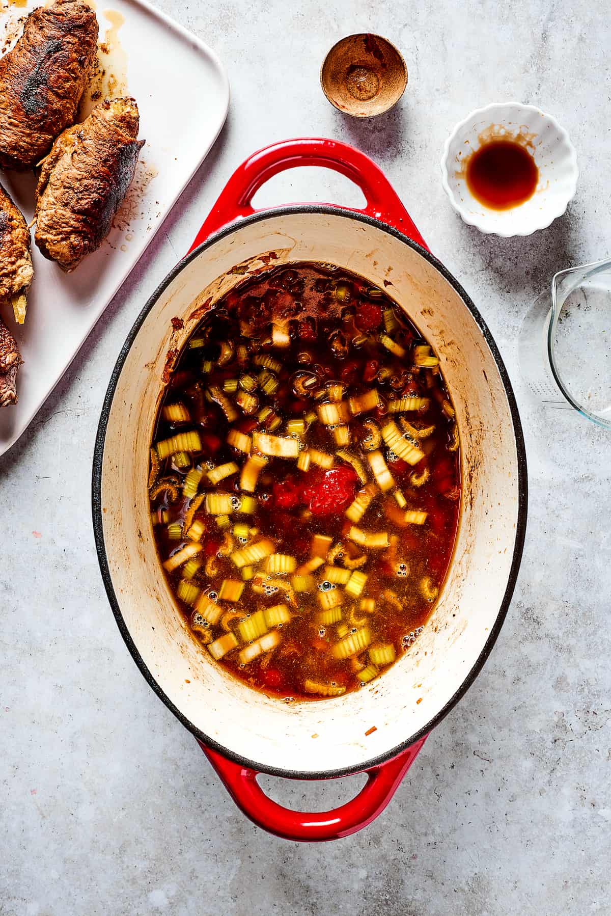 Rich, flavorful Rouladen is a classic German dish. Little meat rolls are stuffed with onions, bacon, and pickles then simmered in gravy. Cooking vegetables for rouladen.
