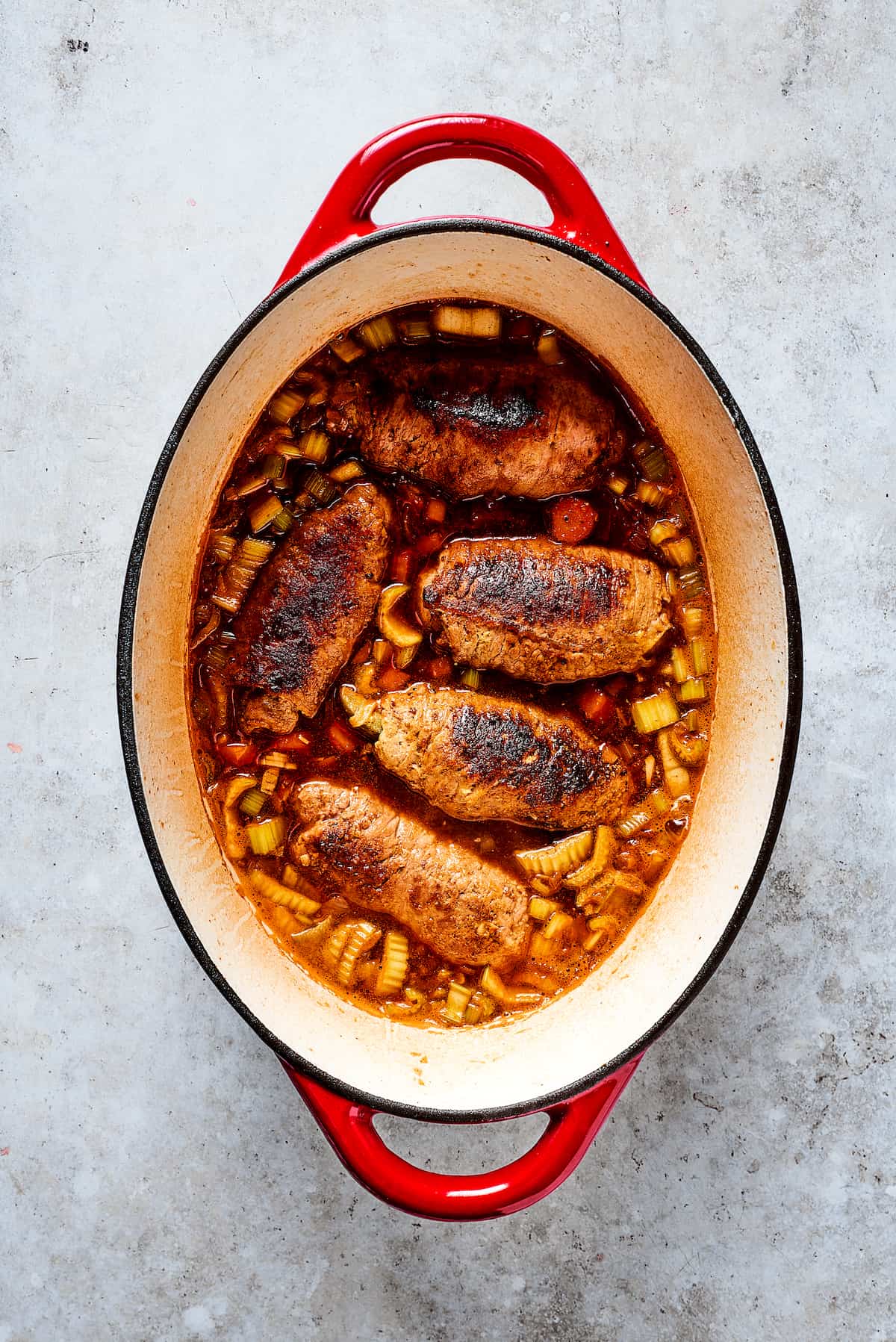 Rich, flavorful Rouladen is a classic German dish. Little meat rolls are stuffed with onions, bacon, and pickles then simmered in gravy. Browning rouladen in a dutch oven.