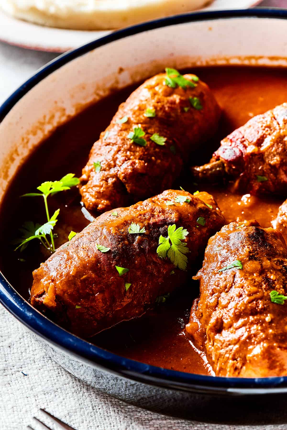Rich, flavorful Rouladen is a classic German dish. Little meat rolls are stuffed with onions, bacon, and pickles then simmered in gravy. Rouladen cooks in gravy.