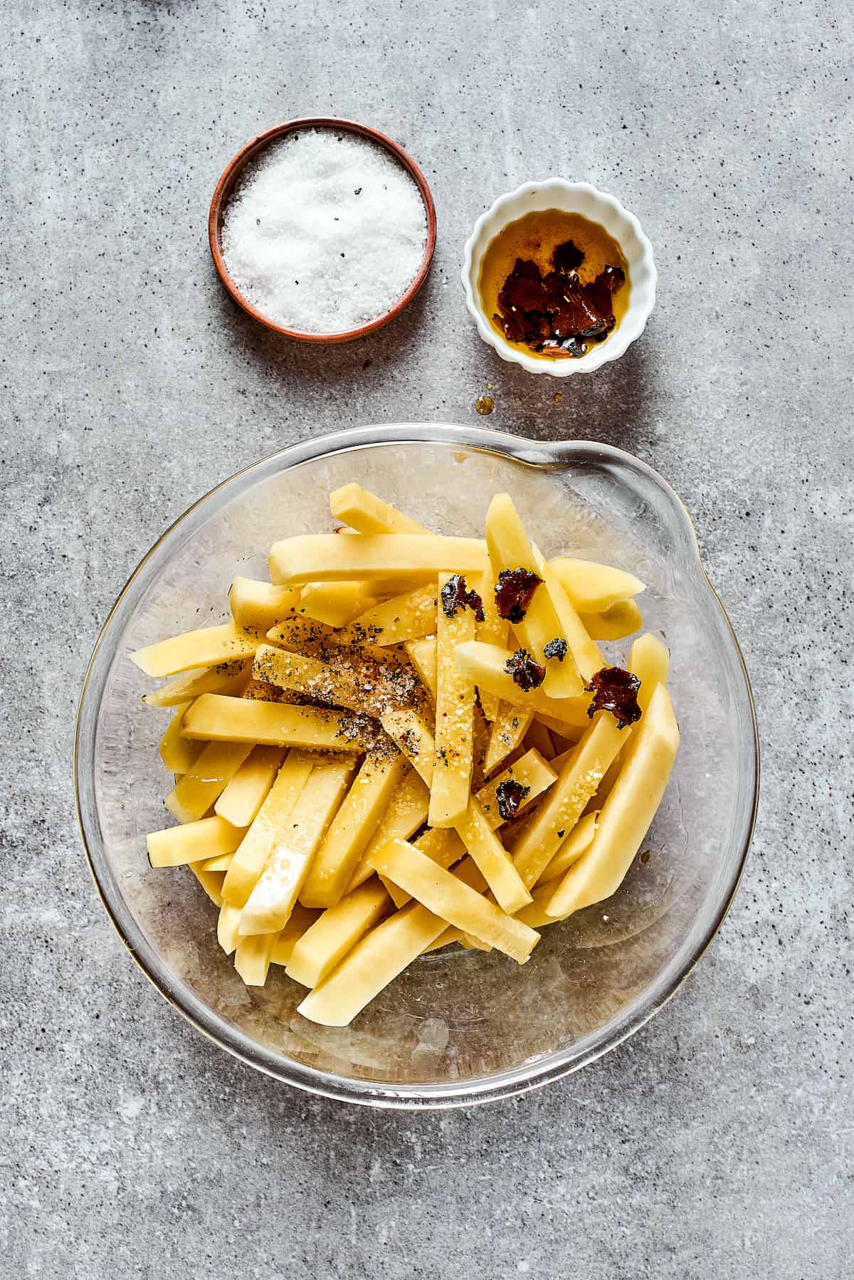 Crispy and flavorful, Truffle Fries may become your new favorite fry! They're touched with truffle salt and a dusting of parmesan cheese. A bowl of cut potatoes for fries with seasonings.