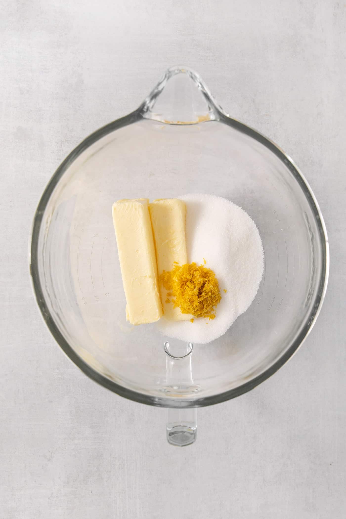 Butter and sugar and lemon zest in a clear bowl.