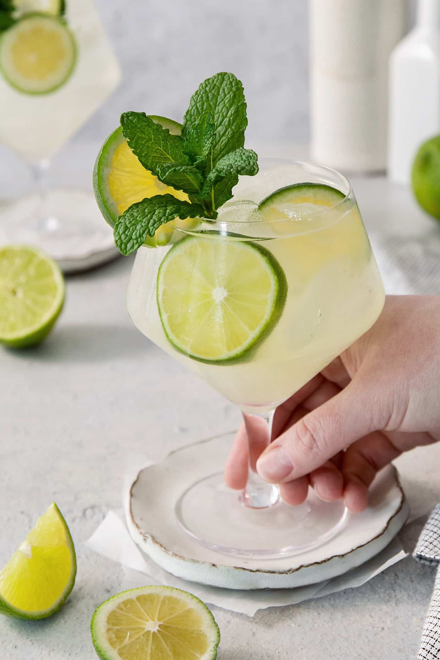 Crisp and refreshing, a Classic Mojito is the only mojito recipe you truly need! Lime juice, mint, and rum make this wonderful cocktail. A hand holds a glass of mojito.
