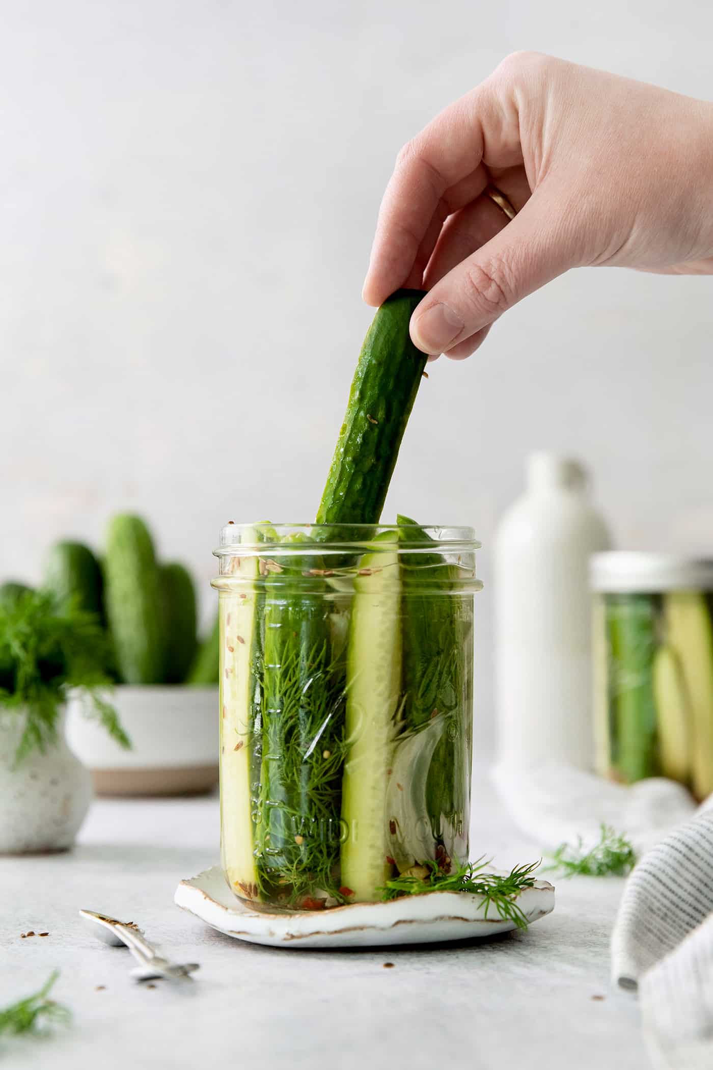 These Refrigerator Dill Pickles require no canning or special equipment, just cucumbers and a simple pickling brine. An easy side or snack! A hand pulling a dill pickle spear from a jar