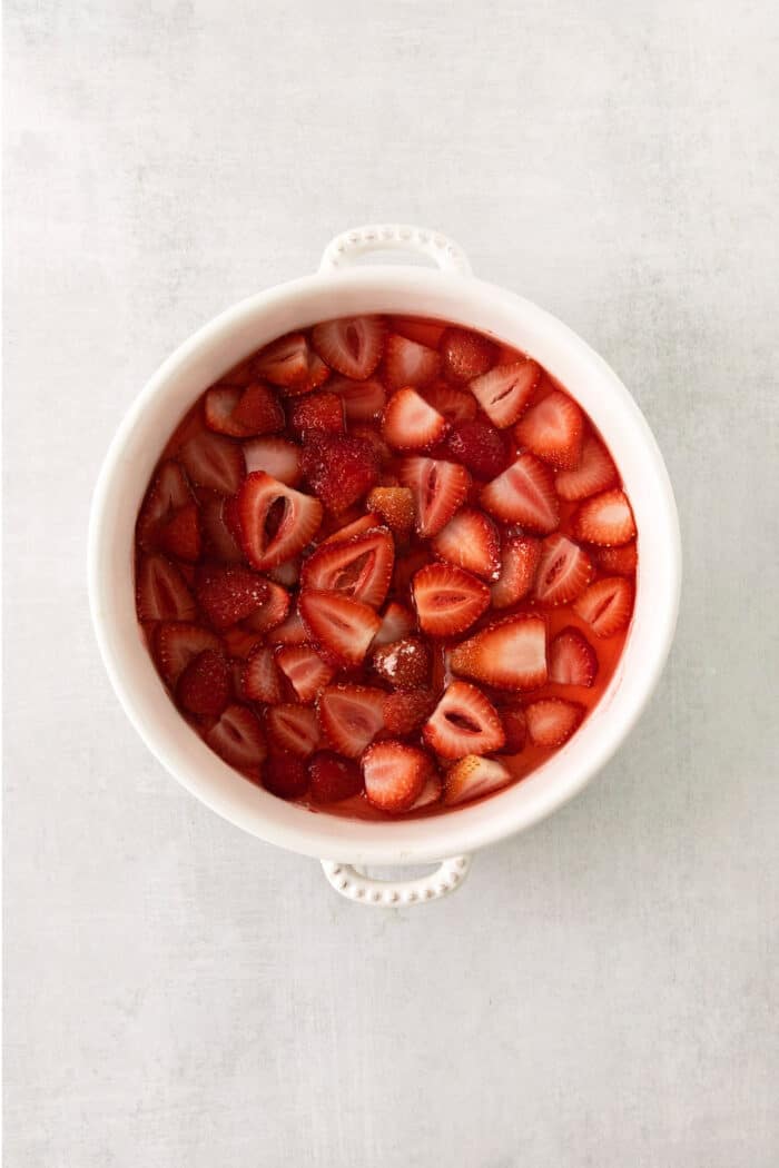 This homemade Crème Fraîche Strawberry Ice Cream is rich and ultra creamy with a gorgeous strawberry swirl folded into a tangy ice cream. Sliced strawberries in a bowl.