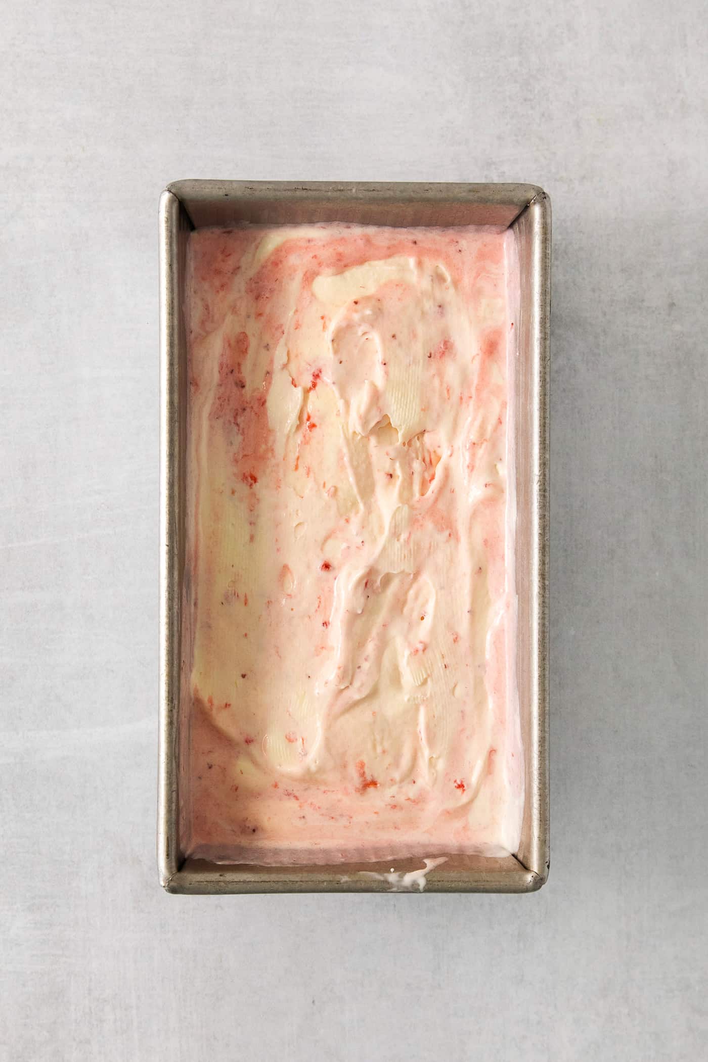 This homemade Crème Fraîche Strawberry Ice Cream is rich and ultra creamy with a gorgeous strawberry swirl folded into a tangy ice cream. Crème fraîche strawberry swirl ice cream in a loaf pan.