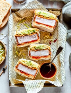 Close up of a stack of katsu sandos and tonkatsu sauce.
