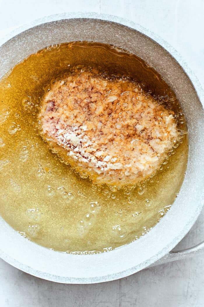 Tender, juicy Pork Katsu is always welcome on my dinner table! This Japanese dish deep fries breaded pork loin until crispy. Frying pork in oil for pork katsu.