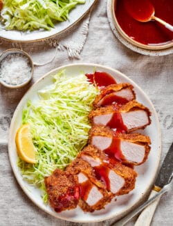 Pork katsu with shredded cabbage and lemon with tonkatsu sauce on the side.