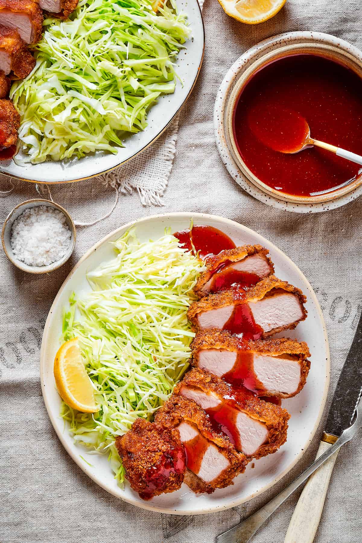 Tender, juicy Pork Katsu is always welcome on my dinner table! This Japanese dish deep fries breaded pork loin until crispy. Pork katsu with shredded cabbage and lemon with tonkatsu sauce on the side.