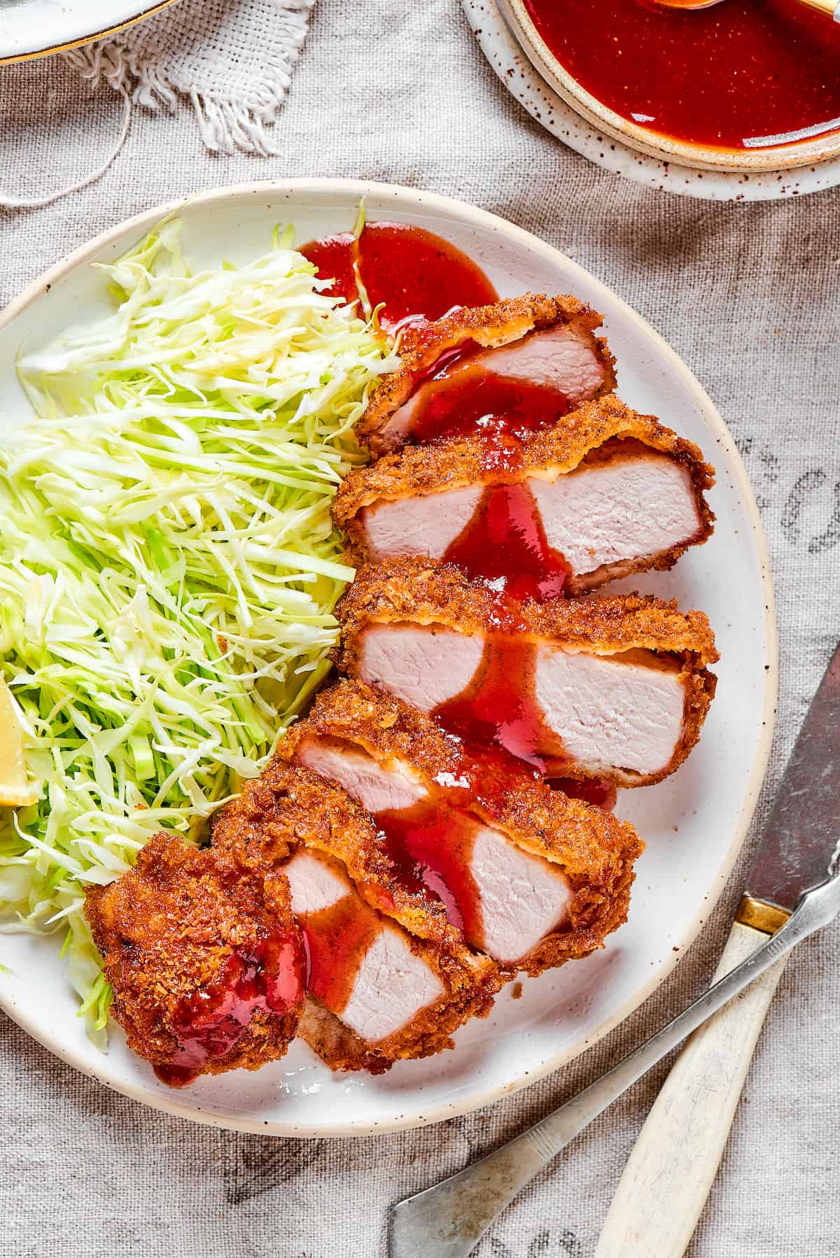 Tender, juicy Pork Katsu is always welcome on my dinner table! This Japanese dish deep fries breaded pork loin until crispy. Pork katsu with shredded cabbage and lemon.