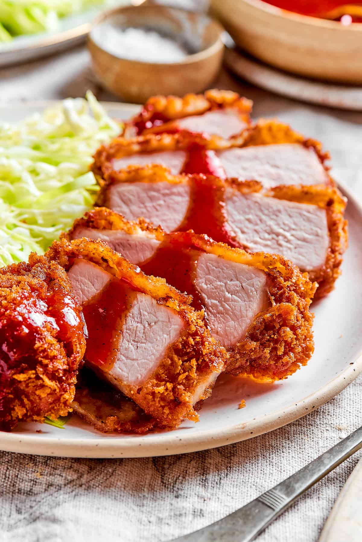 Tender, juicy Pork Katsu is always welcome on my dinner table! This Japanese dish deep fries breaded pork loin until crispy. Slices of pork katsu with shredded cabbage.