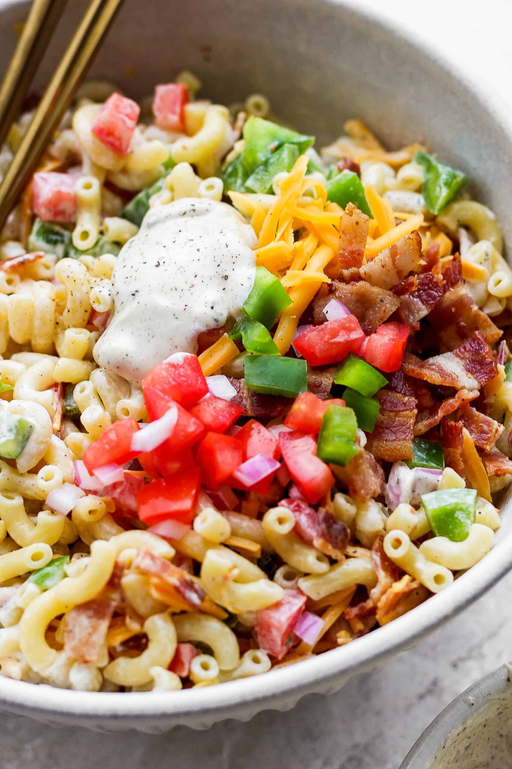 Make this crowd-pleasing Bacon Ranch Pasta Salad for your next bbq! Crispy bacon, and tender pasta will make this potluck side a new favorite. Close up of bacon ranch pasta salad.