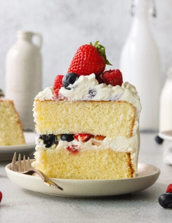 A slice of berry Chantilly cake on a plate with a fork.