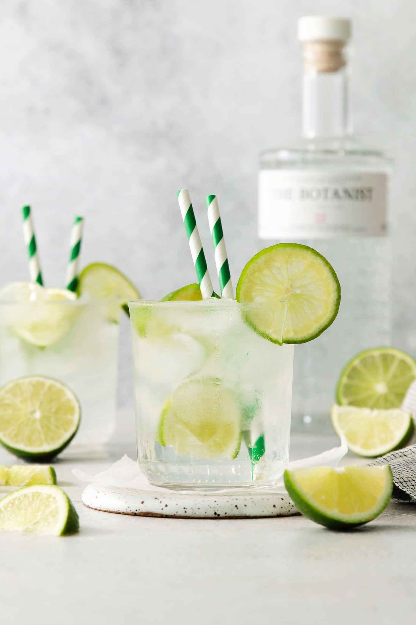 A Classic Gin and Tonic is a must to master. This recipe is for a super simple, super refreshing, and always-in-style cocktail. Glasses of gin and tonic with and lime circles and wedges.