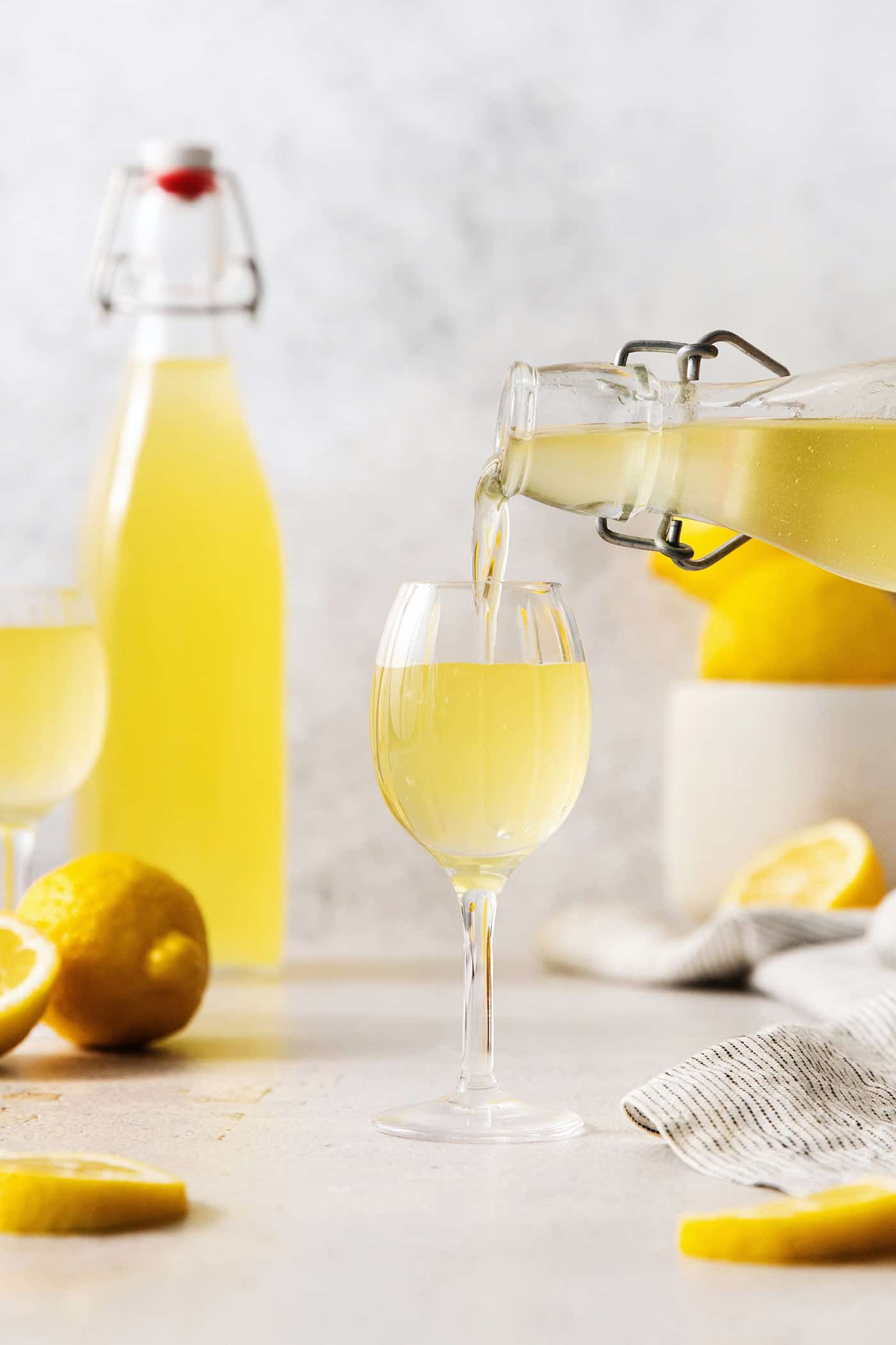 A small glass of this homemade Limoncello, served straight from the freezer, is the loveliest end to a meal. A bottle pours limoncello into a glass.