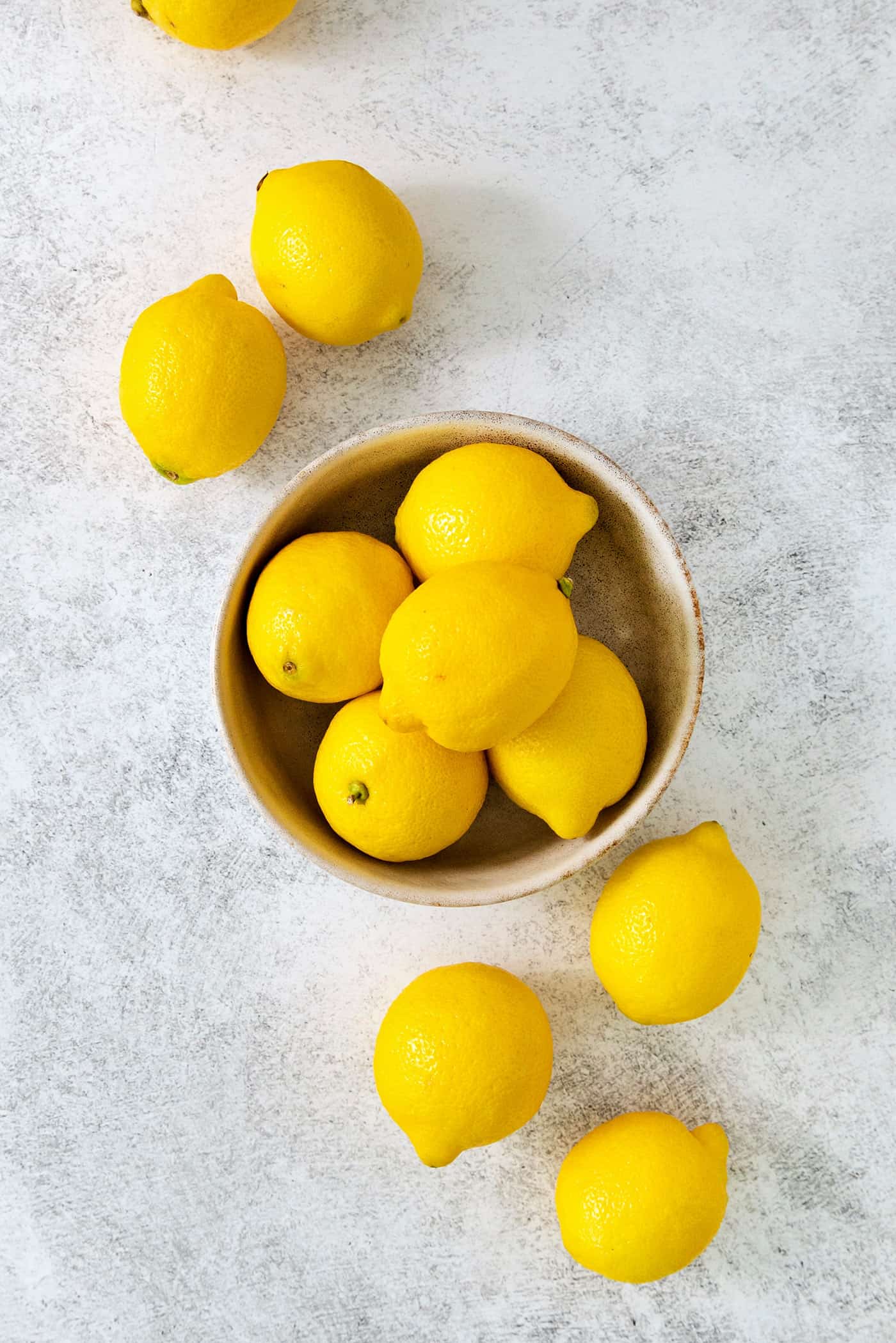A small glass of this homemade Limoncello, served straight from the freezer, is the loveliest end to a meal. A bowl of lemons with lemons next to it.