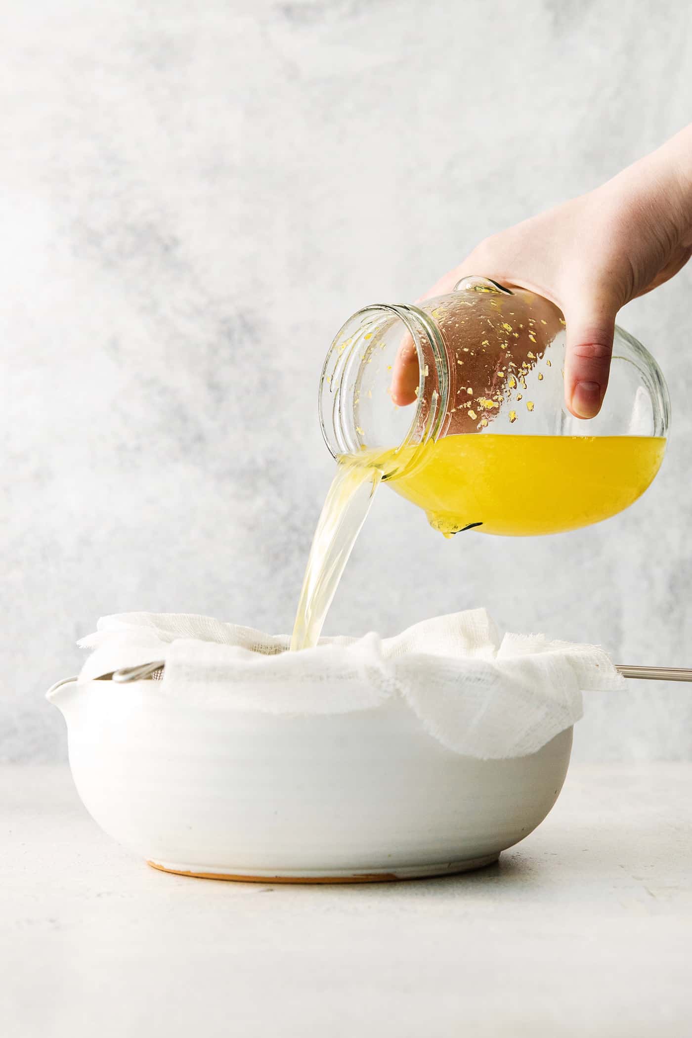 A small glass of this homemade Limoncello, served straight from the freezer, is the loveliest end to a meal. Pouring the lemon-vodka mixture through cheesecloth.