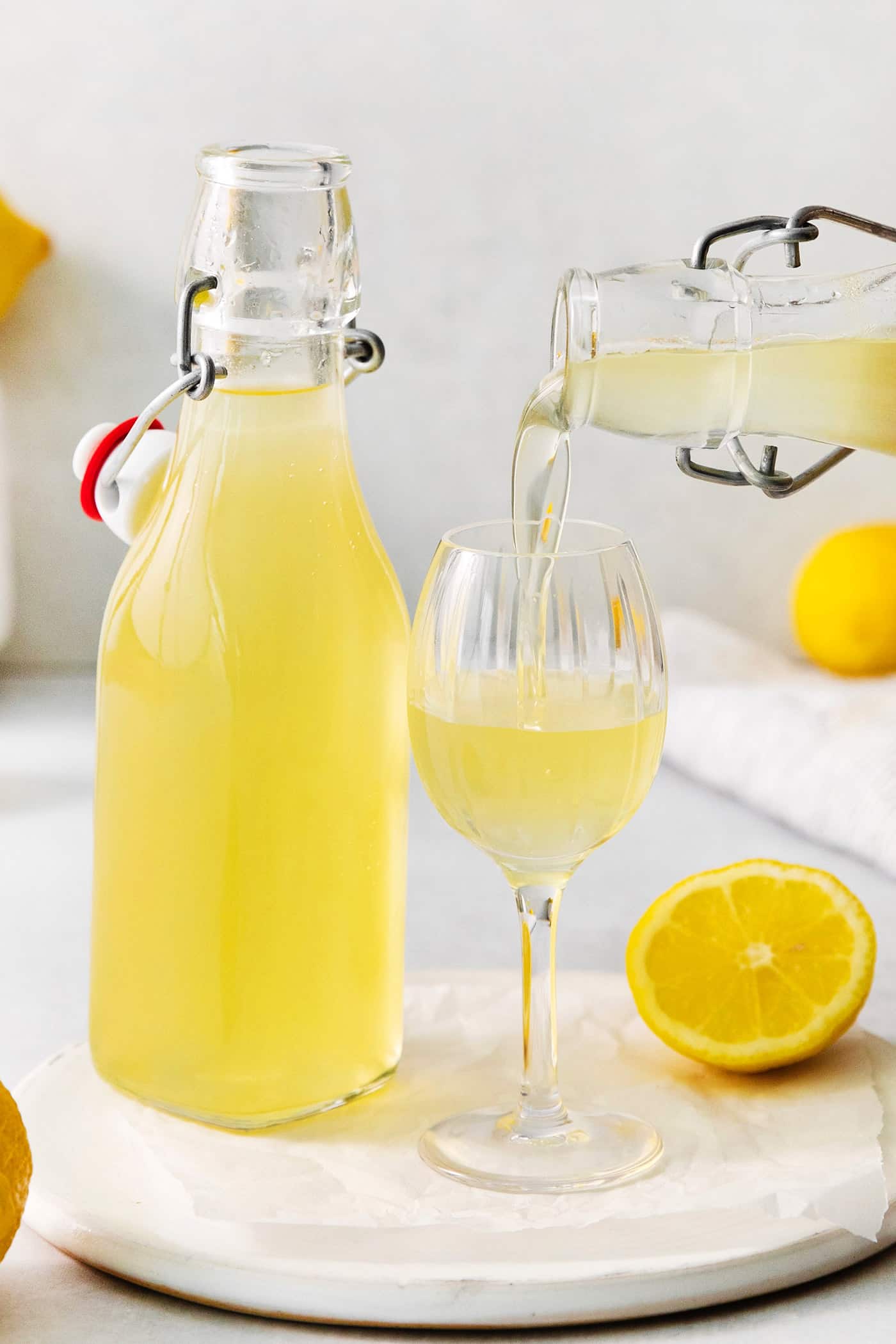 A small glass of this homemade Limoncello, served straight from the freezer, is the loveliest end to a meal. A bottle of limoncello next to a glass of limoncello.