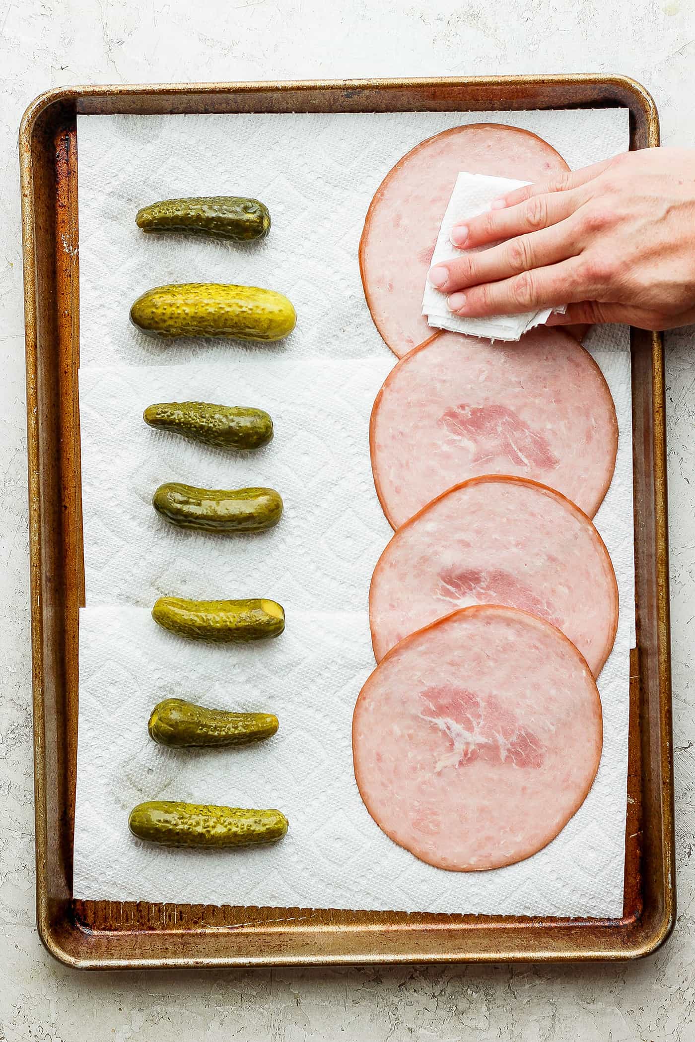 ickle Roll Ups are a 3-ingredient appetizer that's perfect for a party snack or anytime! Tangy pickles are filled with cream cheese and ham. Patting ham dry with pickles next to it.