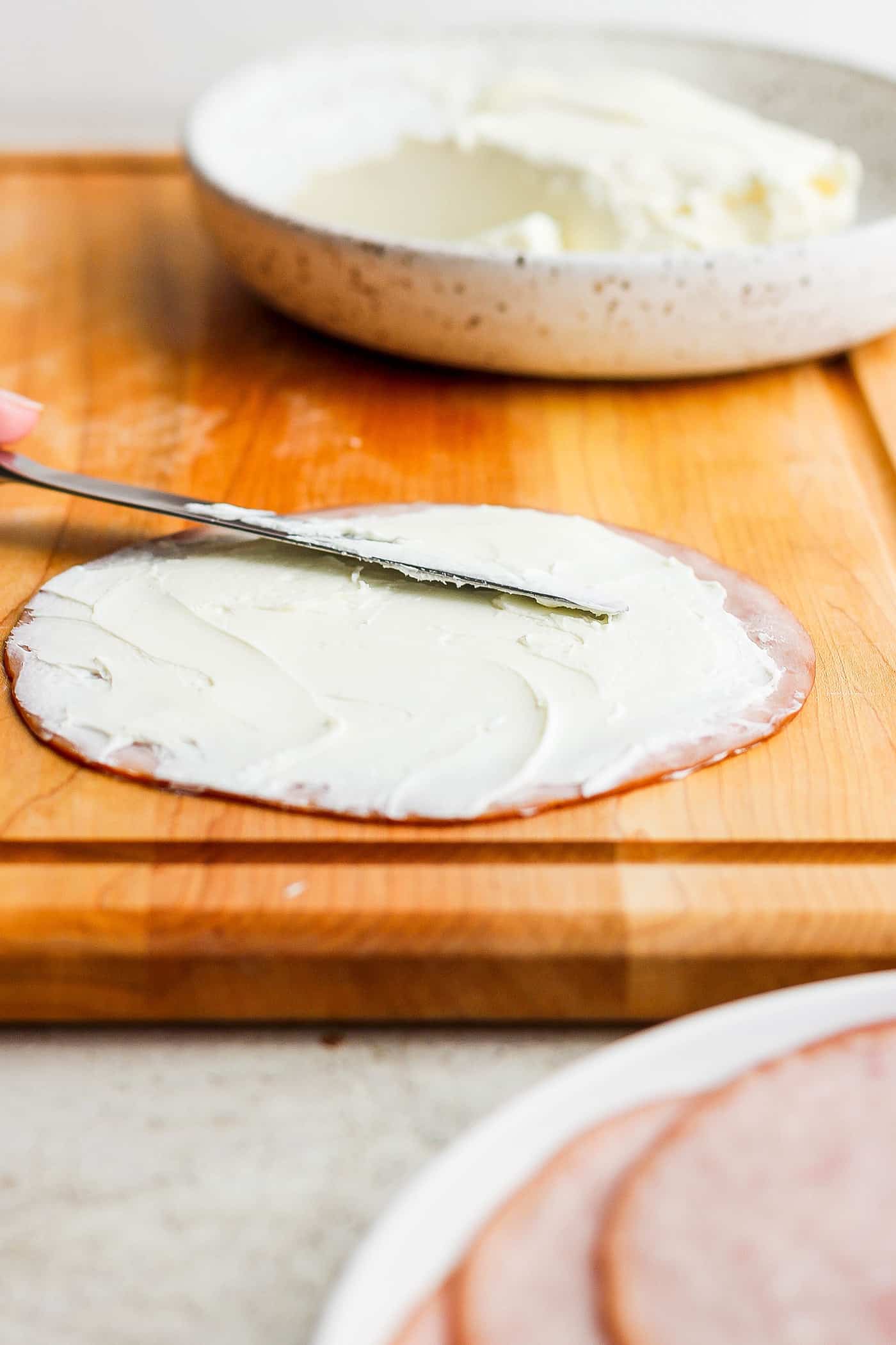 ickle Roll Ups are a 3-ingredient appetizer that's perfect for a party snack or anytime! Tangy pickles are filled with cream cheese and ham. A knife spreads cream cheese on a slice of ham.